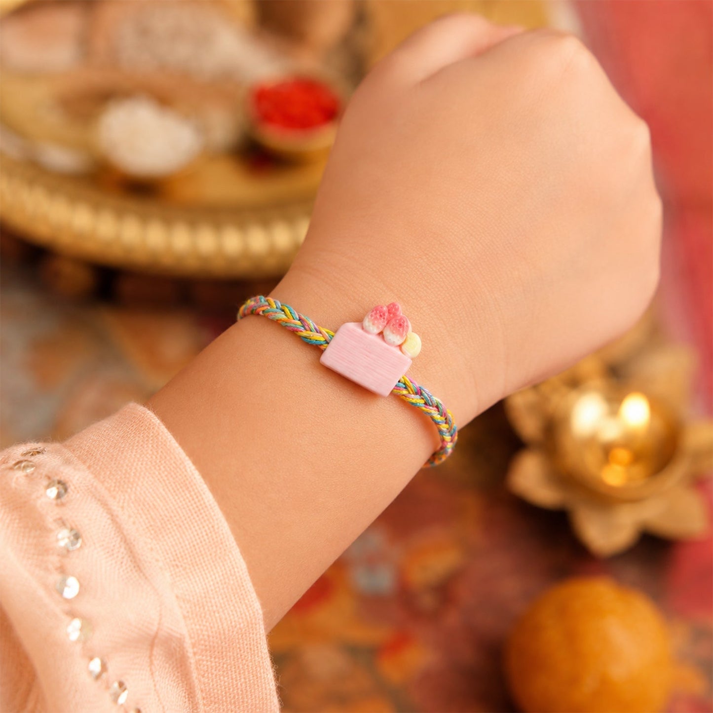 Rakhi tied on brother’s wrist with red thread and strawberry cake charm