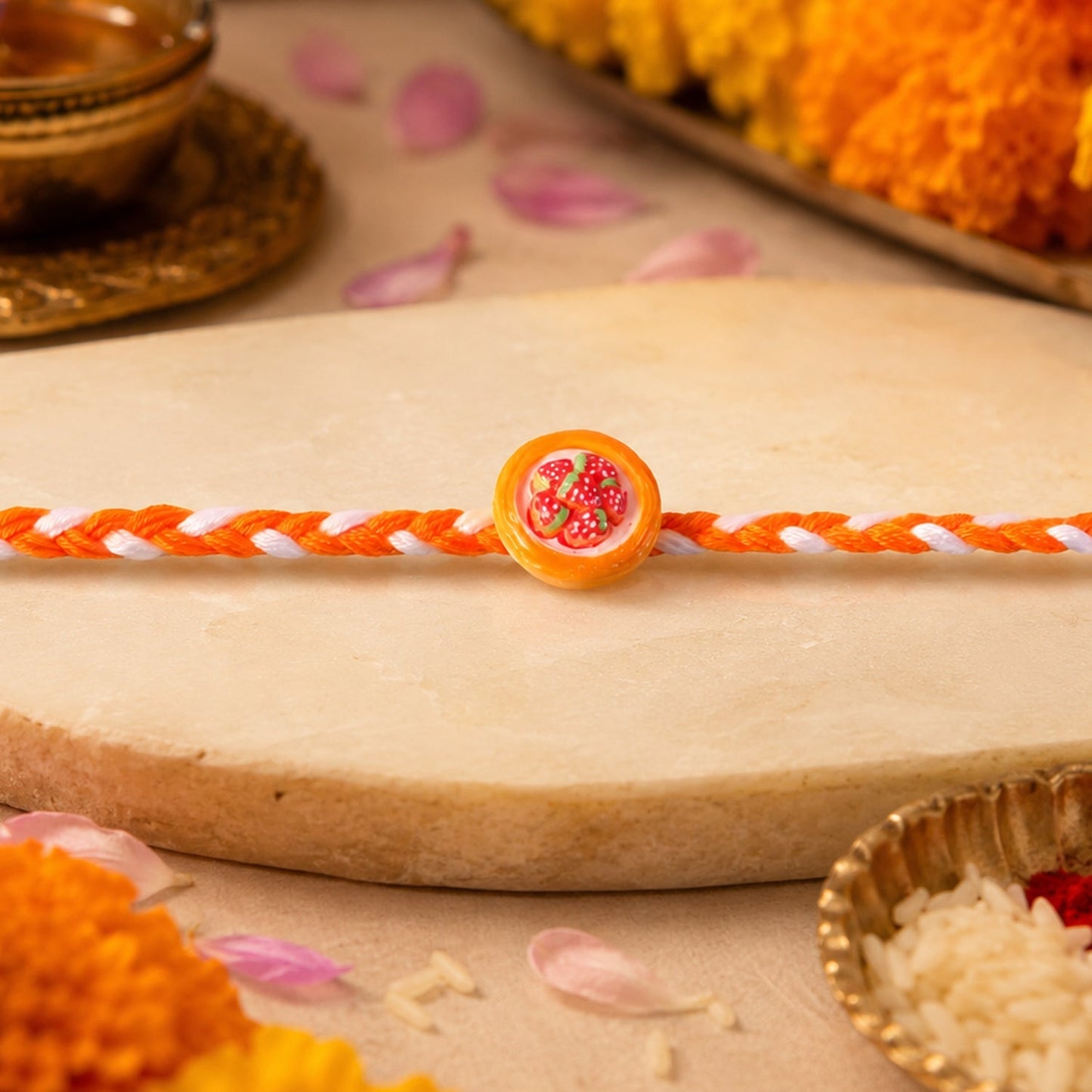 Side angle view of decorative strawberry dori rakhi