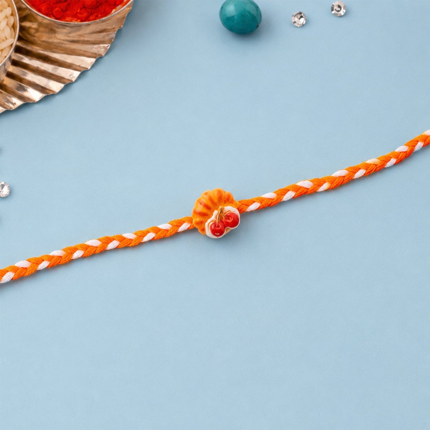 Stylish Dori Rakhi featuring a charming cherry pastry motif.