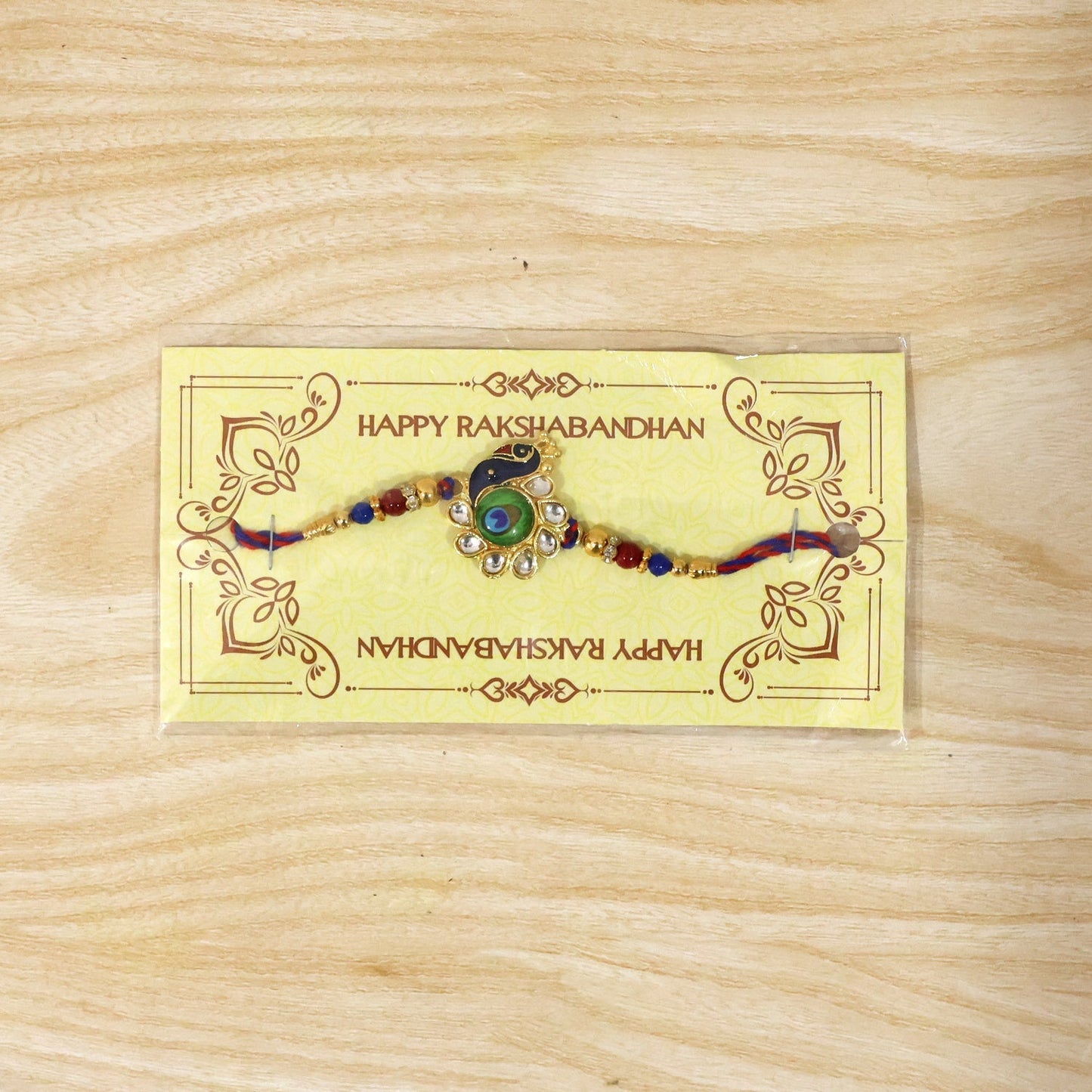 Peacock Feather charm rakhi displayed on white background