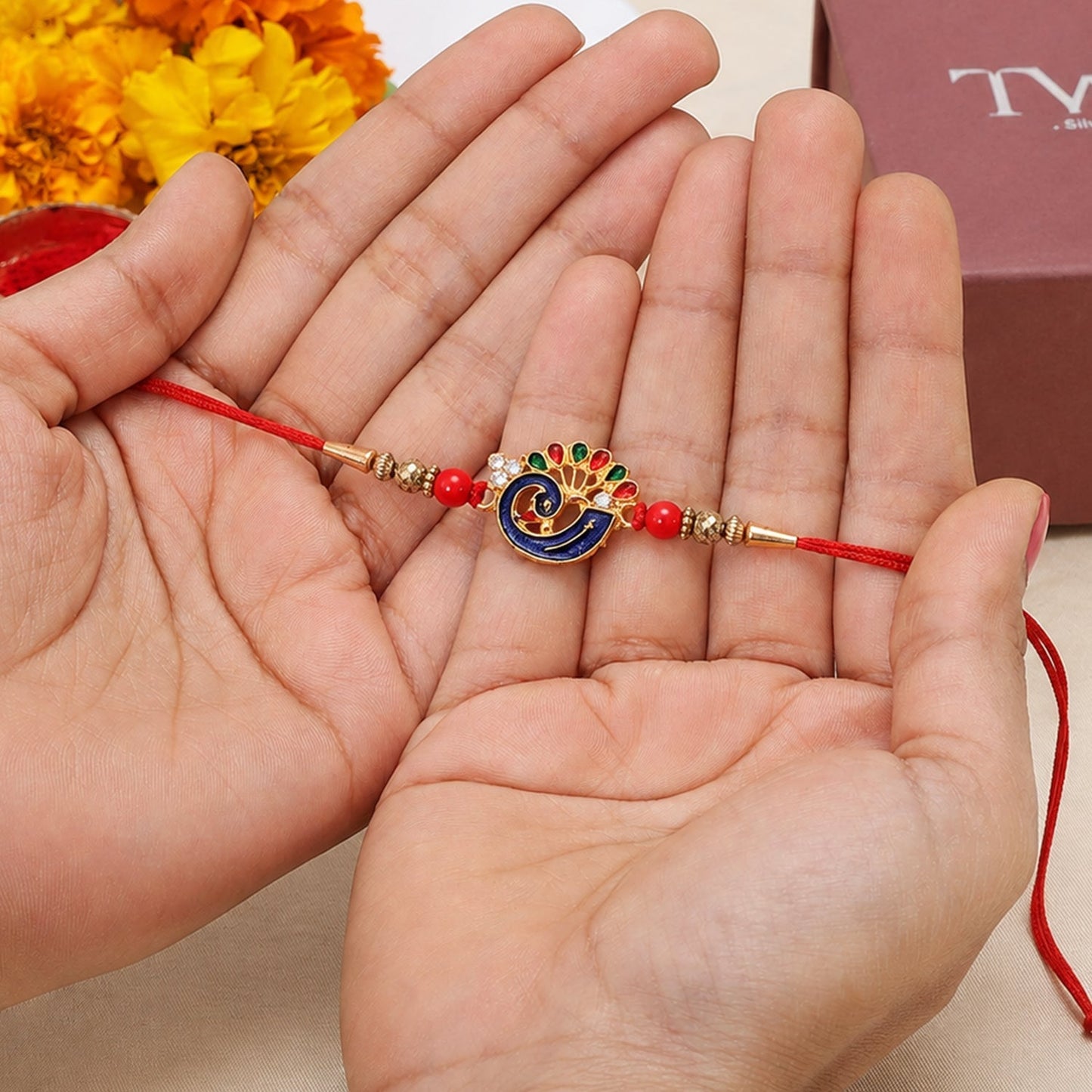 Side view of colorful peacock charm Rakhi with red beads