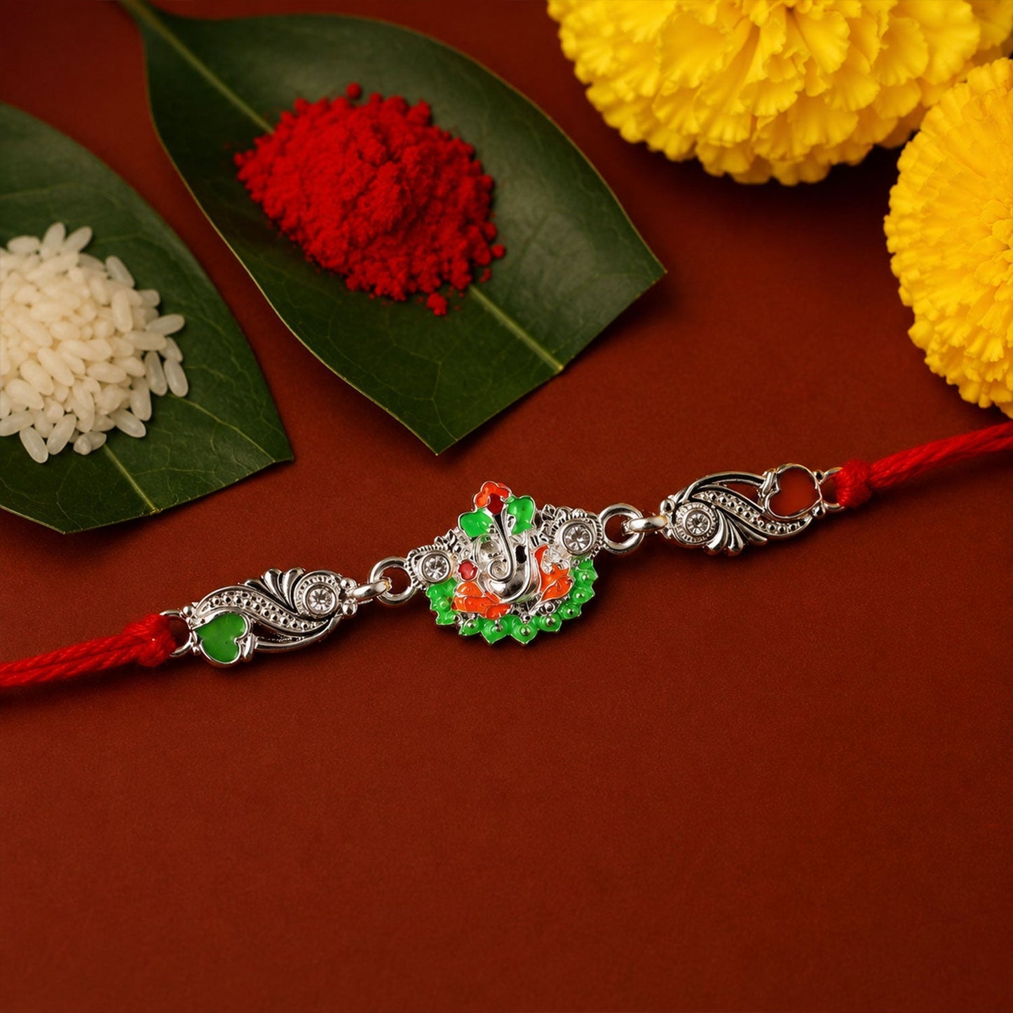 Top view of silver Ganesh charm on red thread rakhi