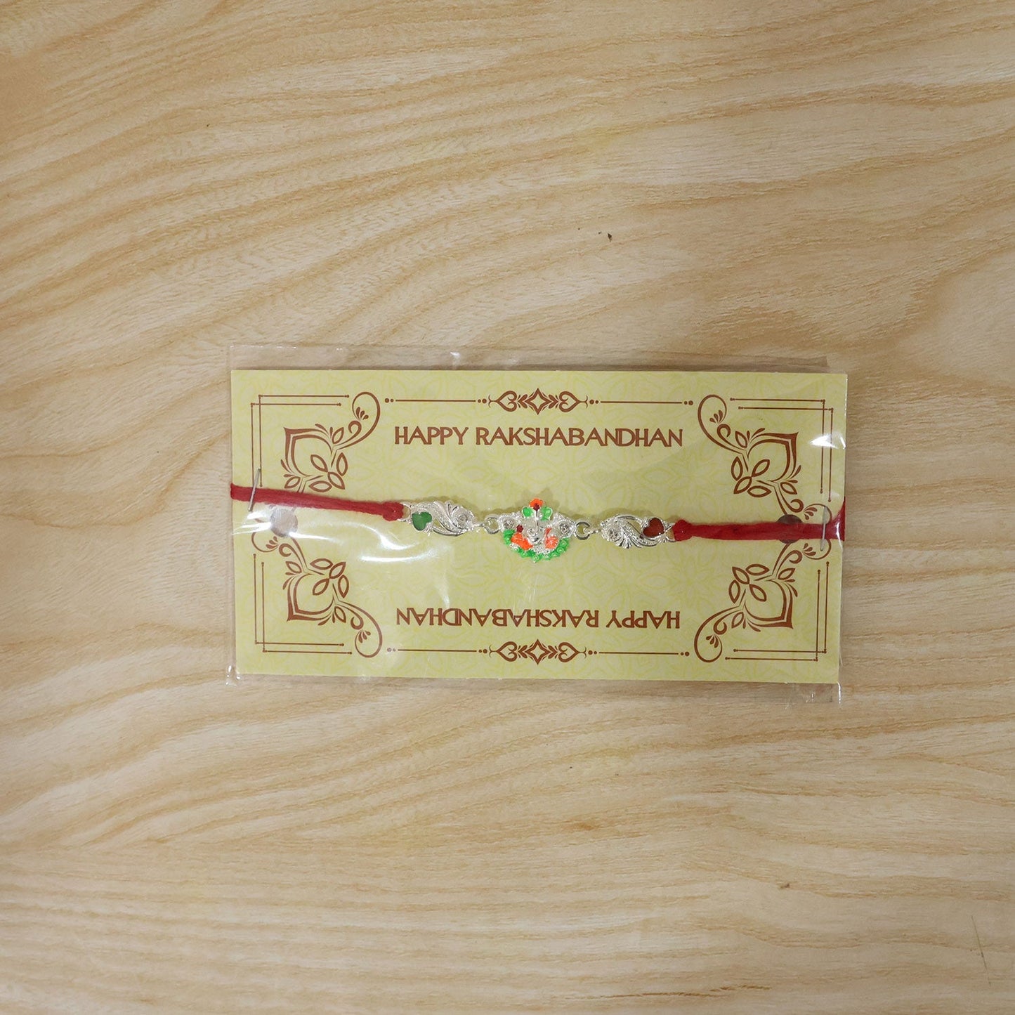 Red dori thread rakhi with elegant silver Ganesh charm