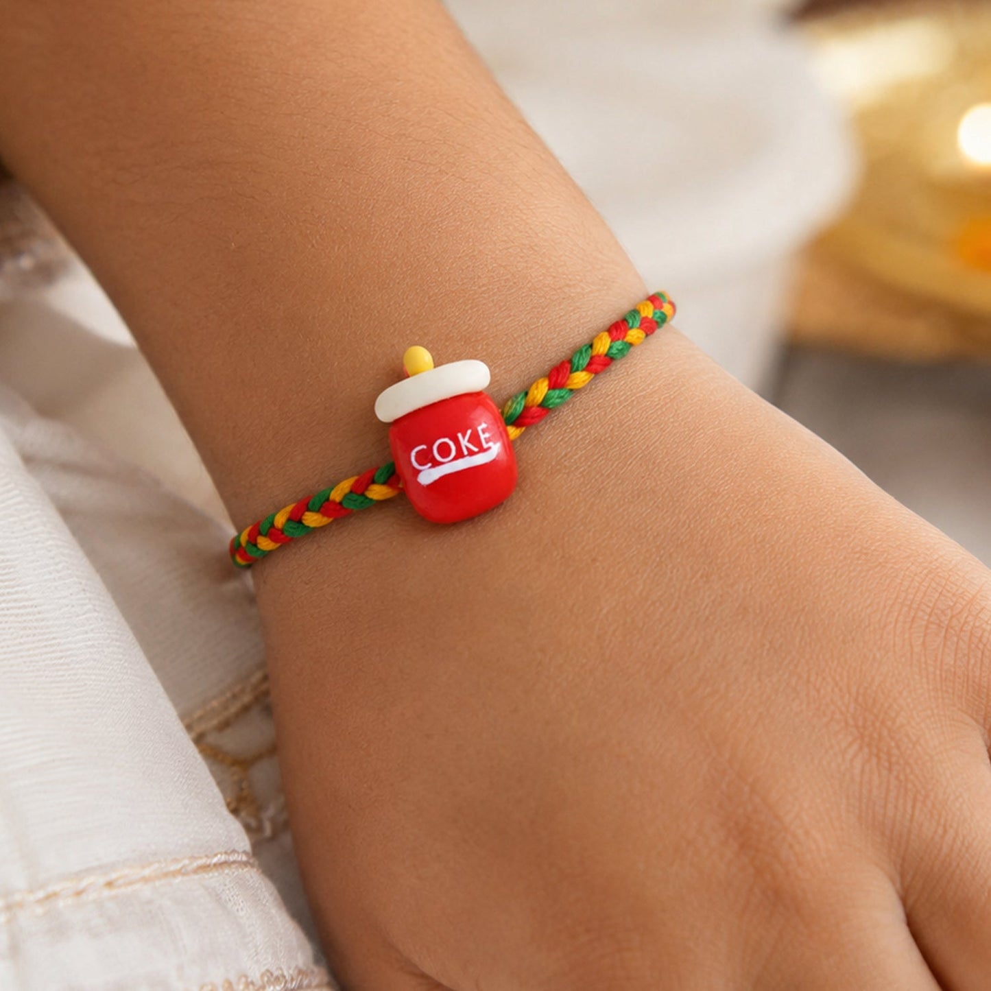 Close-up of Coke bottle charm rakhi detail