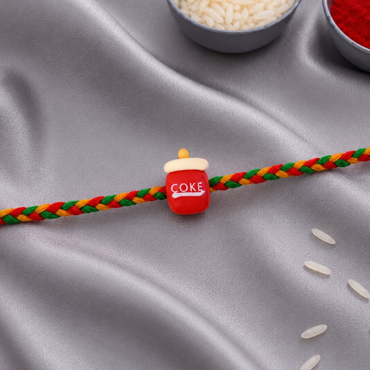 Top view of braided thread rakhi with Coke bottle charm