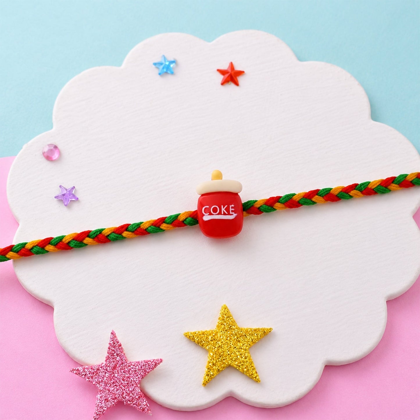 Side view of Coke bottle charm rakhi with braided thread