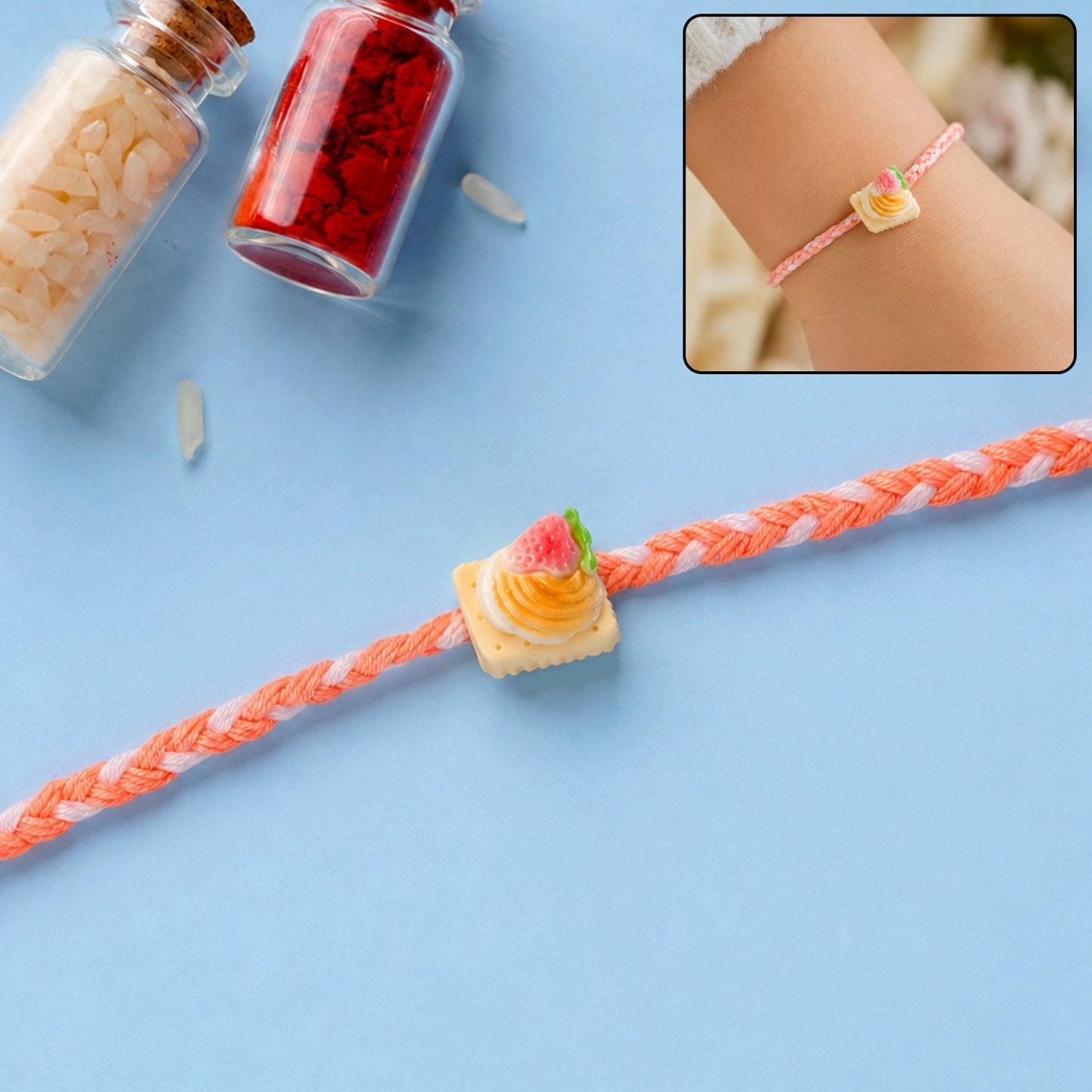Front view of cute strawberry biscuit charm braided Rakhi