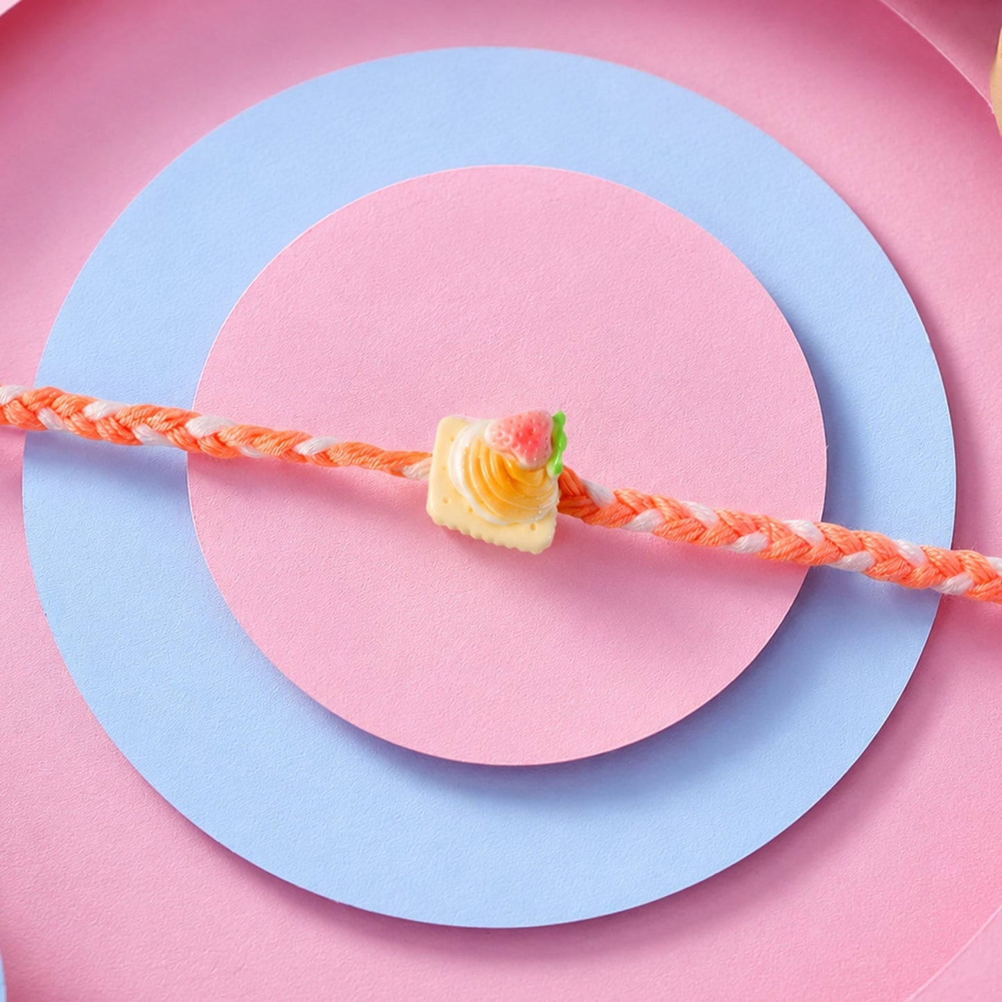 Rakhi with strawberry biscuit charm tied and displayed