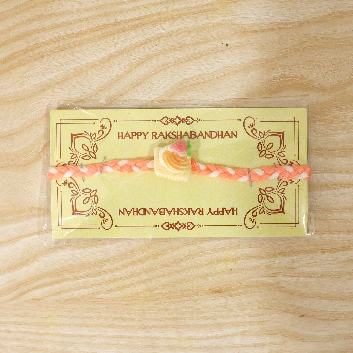 Festive Rakhi featuring strawberry biscuit charm on braided thread