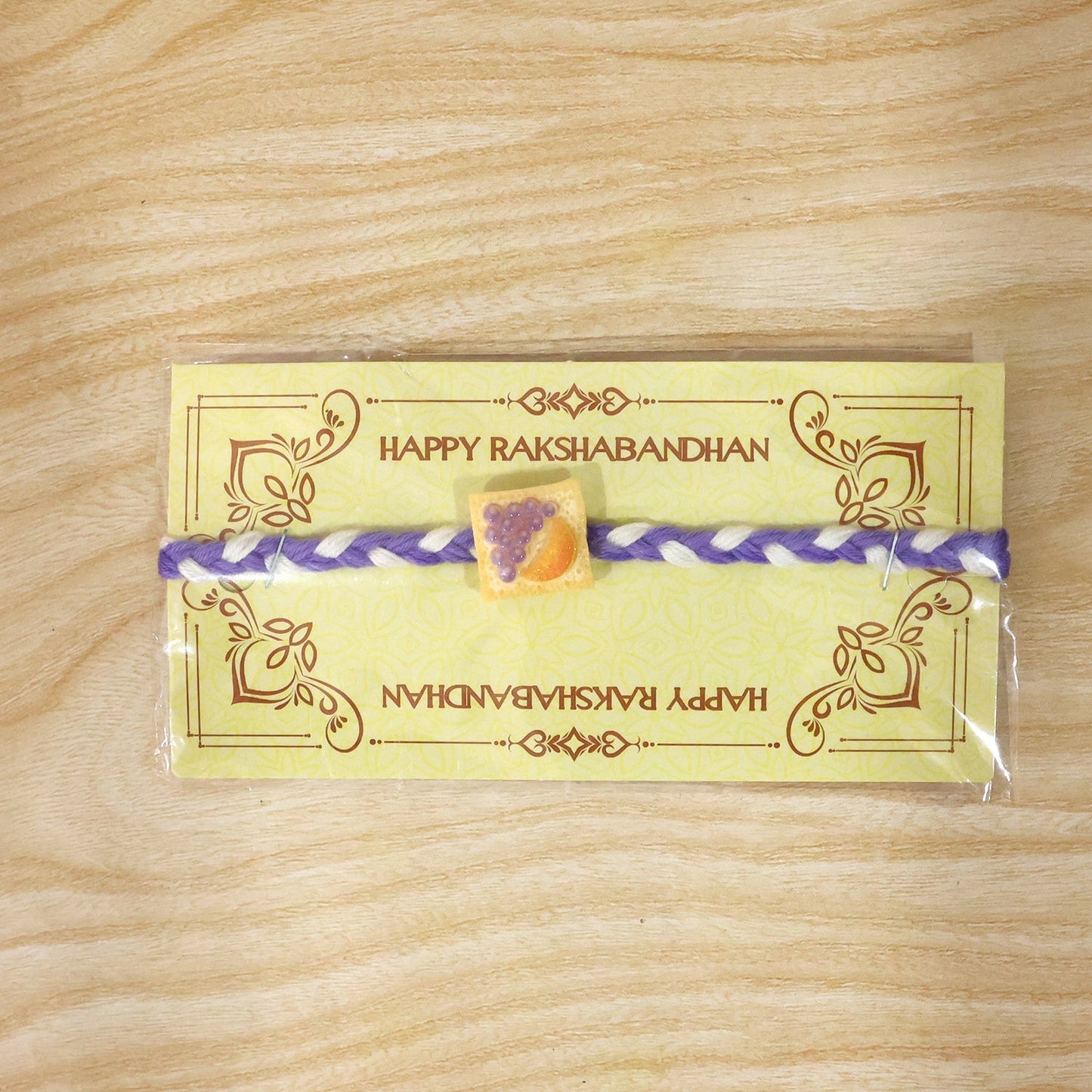 Decorative Fruit Toast Charm Rakhi with braided thread in close-up