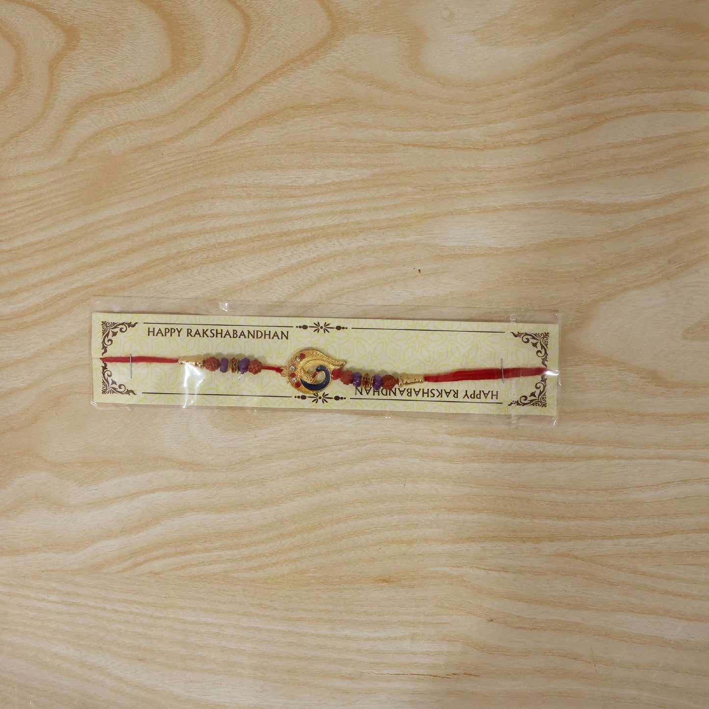 Decorative beads on Golden Mor Feather Rakhi, stylish sibling gift