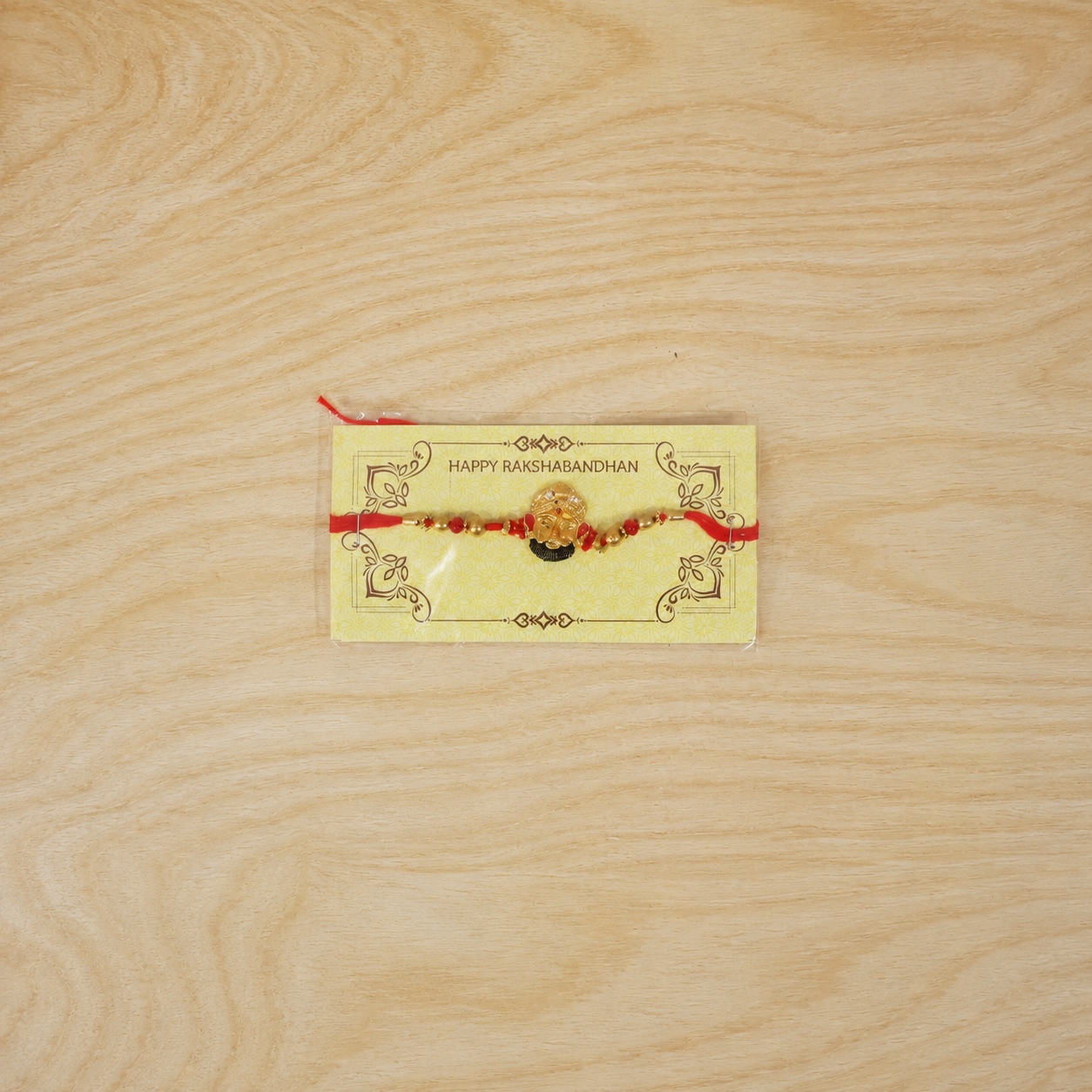 Top view of golden divine face charm rakhi with pearl beads