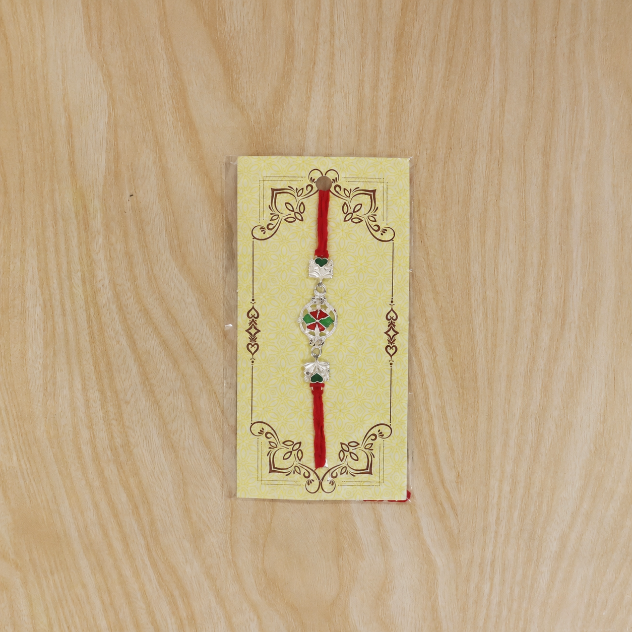Silver pinwheel flower rakhi with decorative dori thread