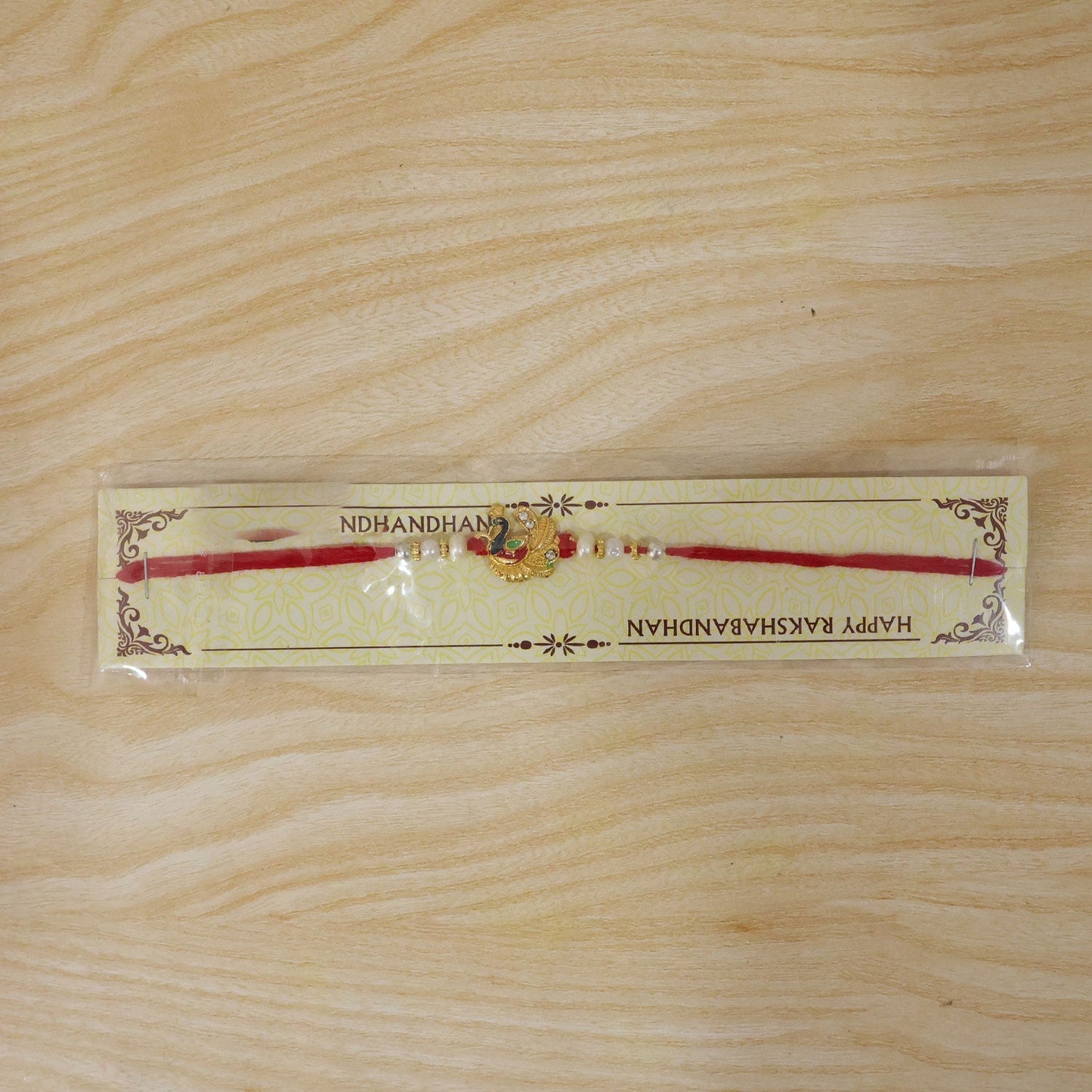 Festive rakhi with peacock design, pearls, and beads, ideal for brother-sister celebration.