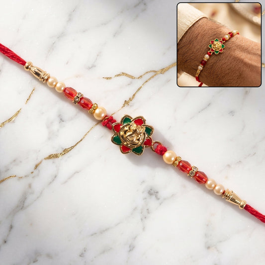 Close-up of traditional golden floral meenakari rakhi with pearls and red beads