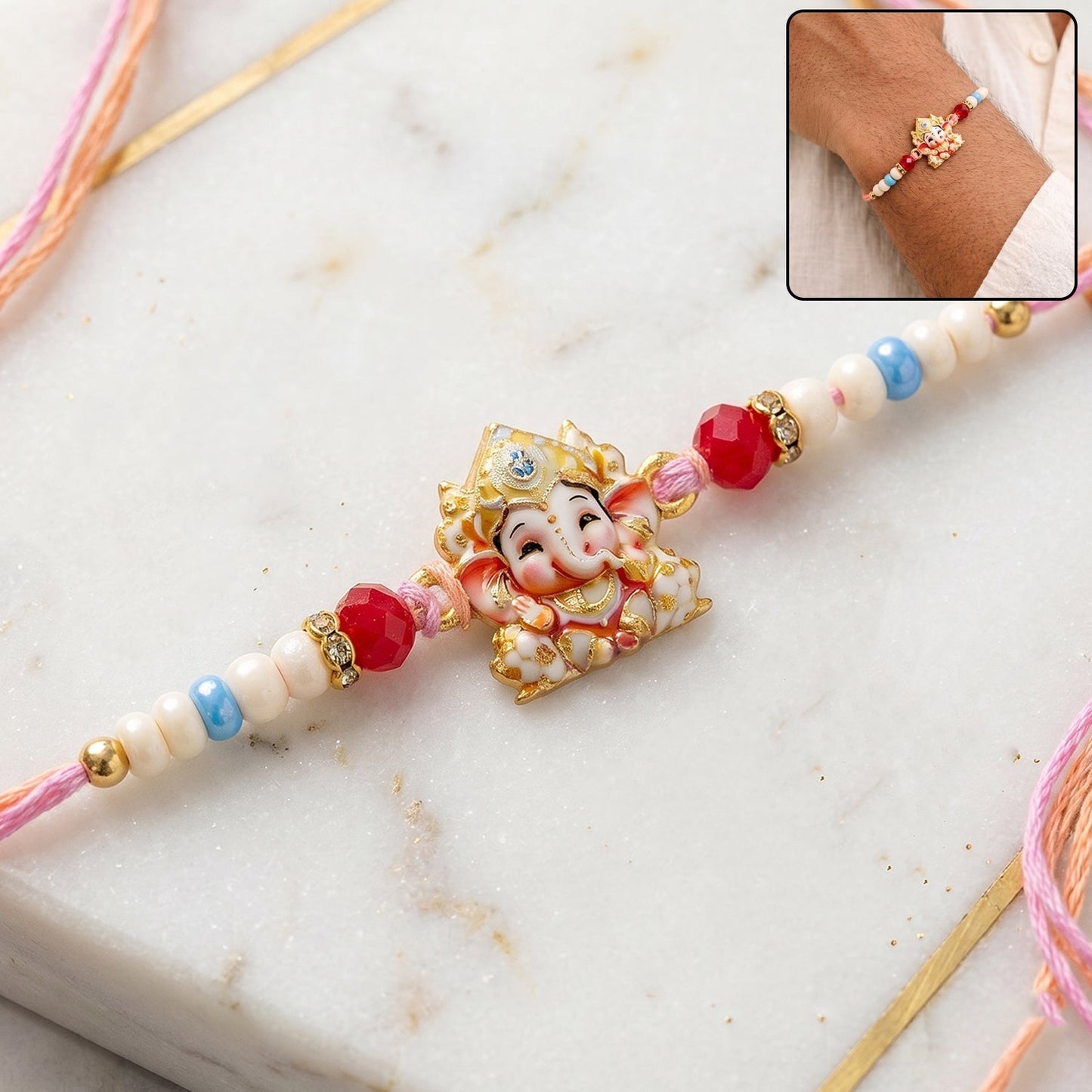 Close-up of a golden Ganesha Rakhi with colourful beads and red thread.