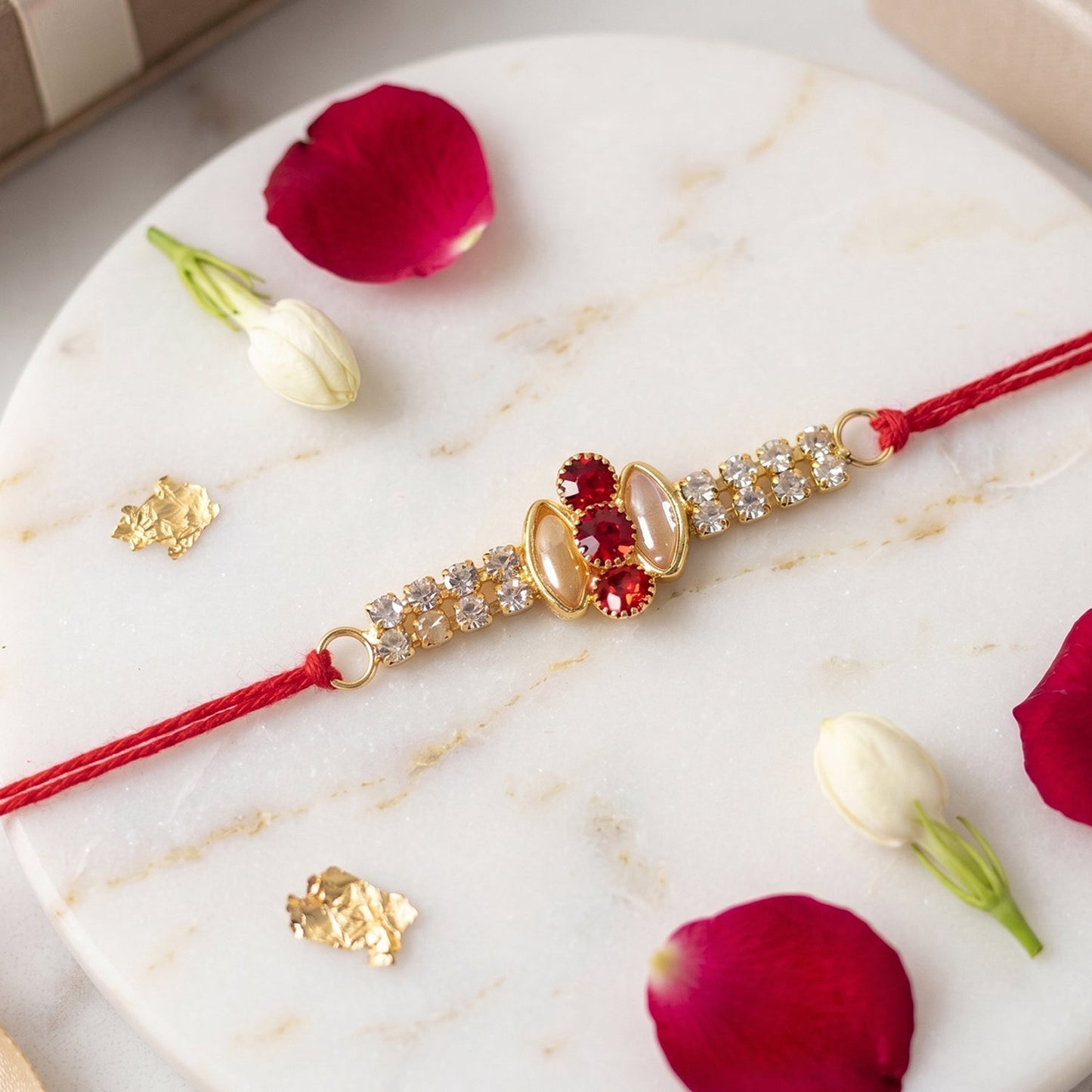 Gold Rakhi with pink stone & AD studs displayed on festive surface