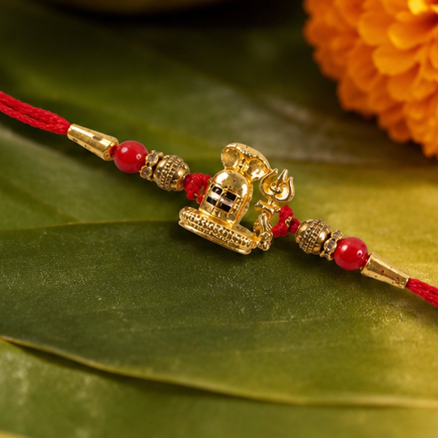 Close-up of an antique golden Shivling Rakhi with red beads.