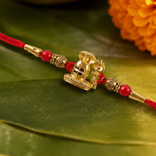 Close-up of an antique golden Shivling Rakhi with red beads.