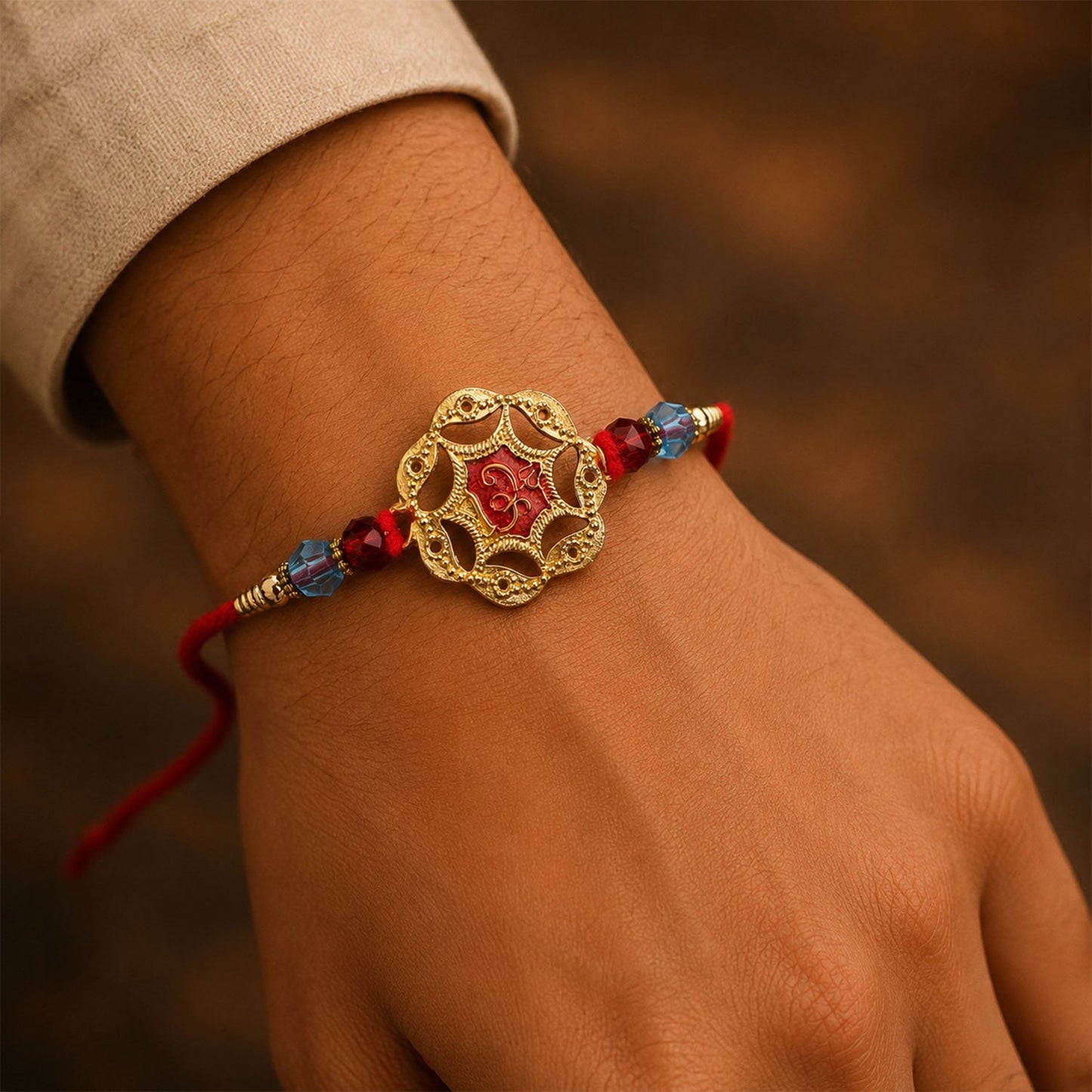 Angled view of stylish red stone Rakhi, highlighting thread work and golden accents.