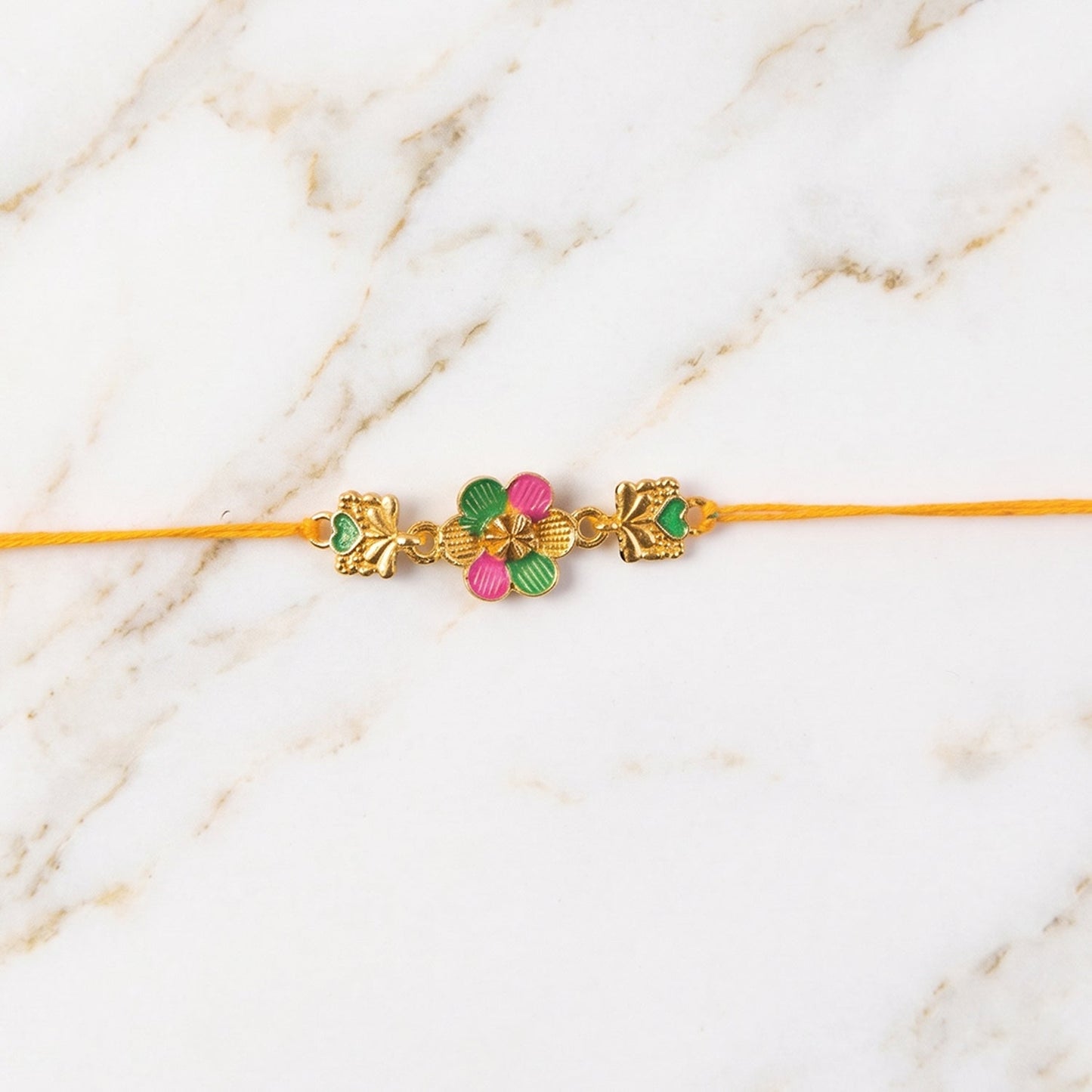 Central flower motif and golden accents on the Golden Meenakari Rakhi.