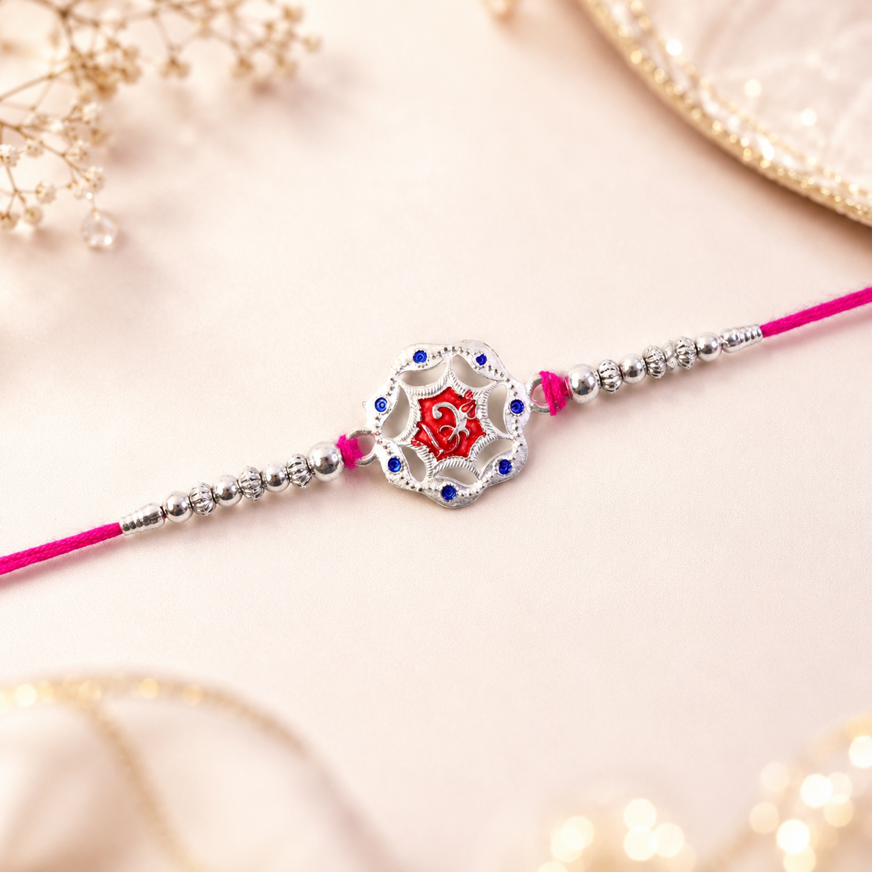 Close-up of the elegant silver-tone floral rakhi design and its red stone detail.