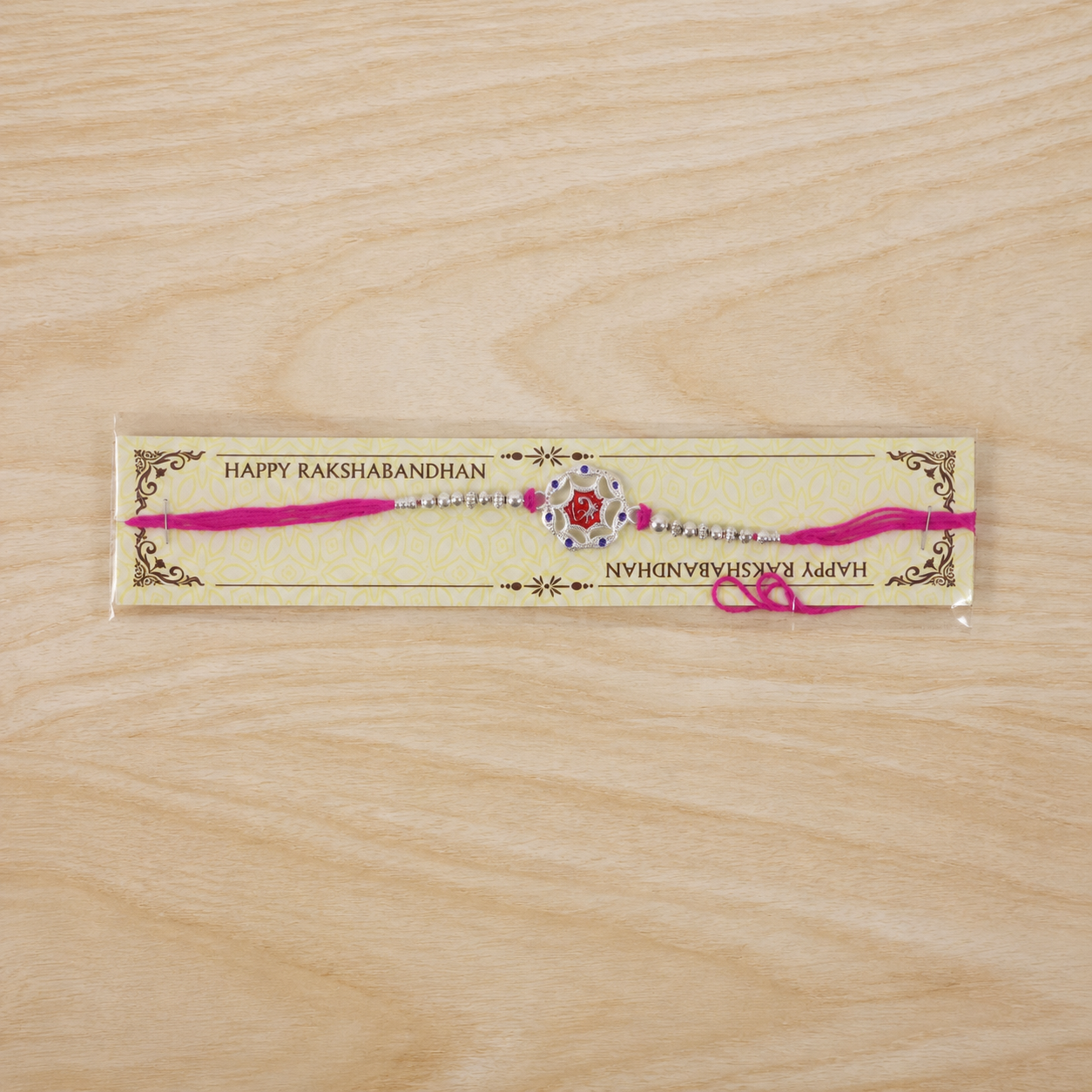 Overhead view of the silver-tone floral rakhi, emphasizing its central red stone.