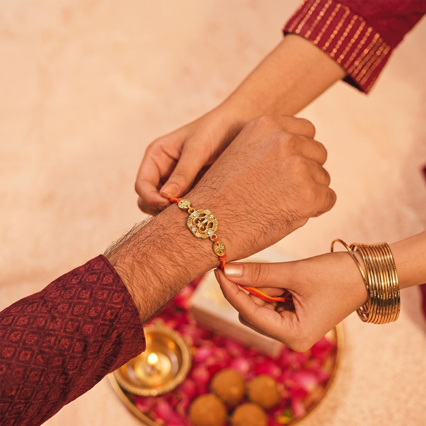 Traditional Rakhi with a golden Om and leaf design, displayed elegantly on a white surface.