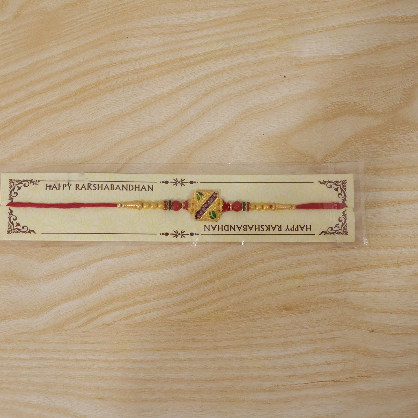 Side view of the golden square Meenakari Rakhi showcasing beadwork and thread.