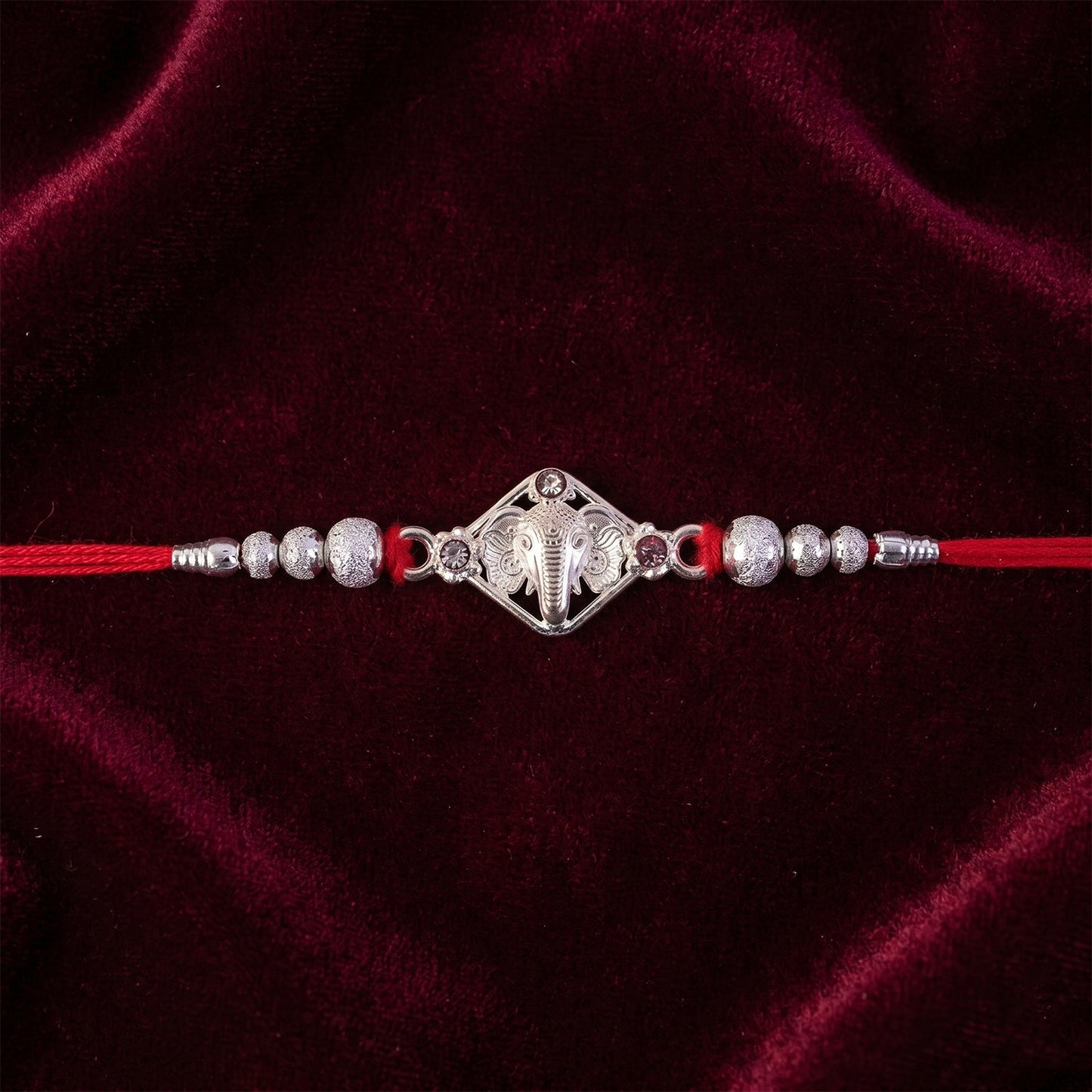 Side view of Ganesha Rakhi highlighting its silver and red stone elements.