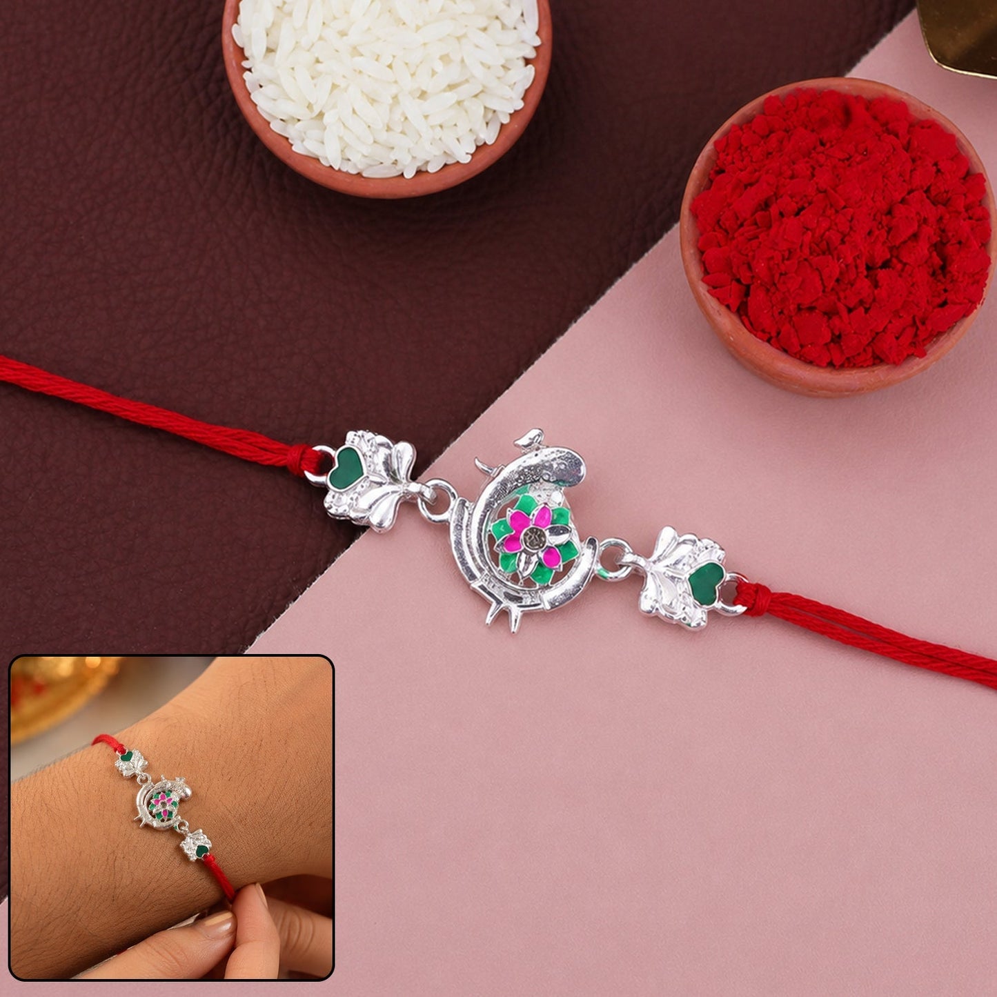 Close-up of silver peacock meenakari rakhi with green and pink enamel detailing