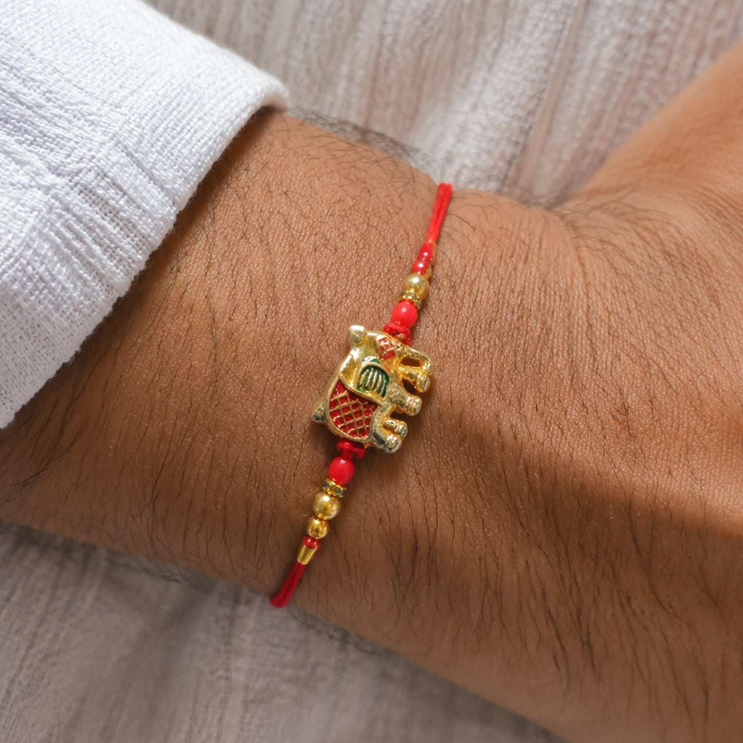 Product image of Gold Elephant Charm Rakhi with beads and red thread