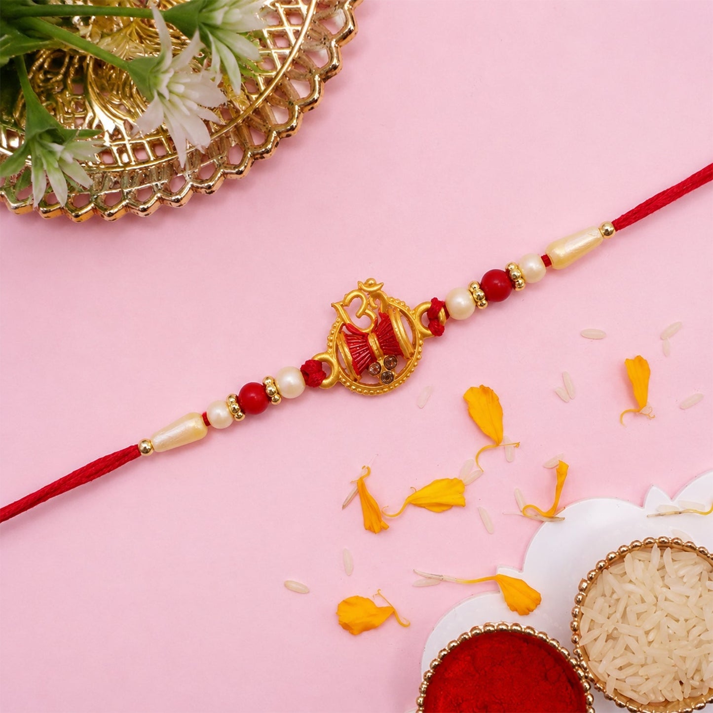 Close-up of red thread and pearl bead rakhi design.