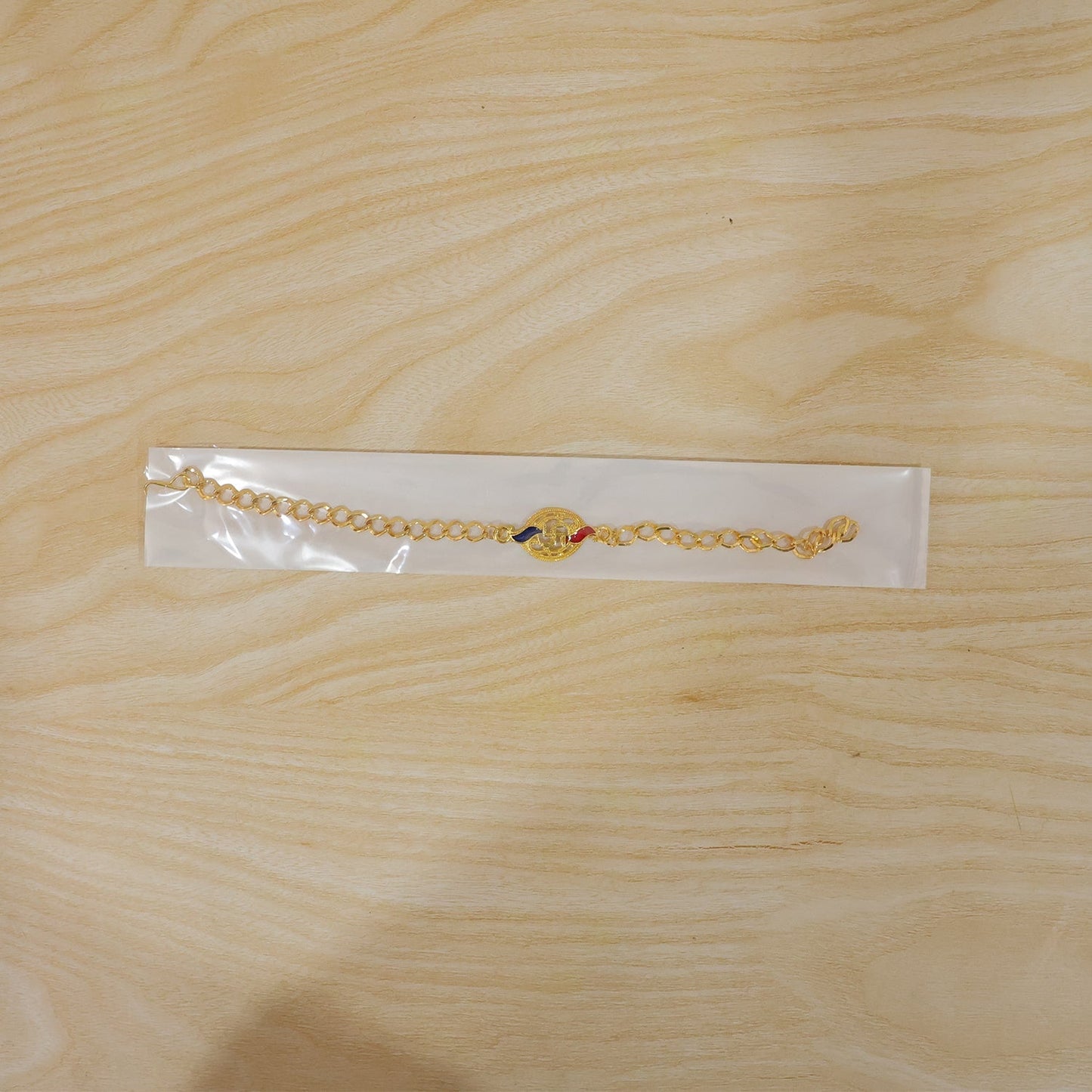 Full bracelet view of Swastik enamel gold-tone rakhi