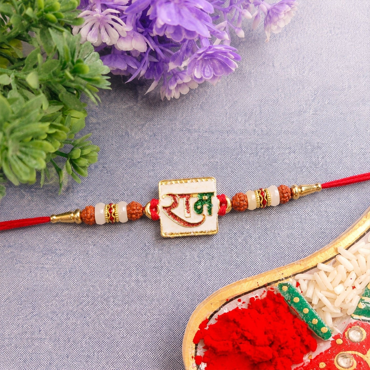 Close-up of Ram Text Gold Tone Rakhi with thread detail
