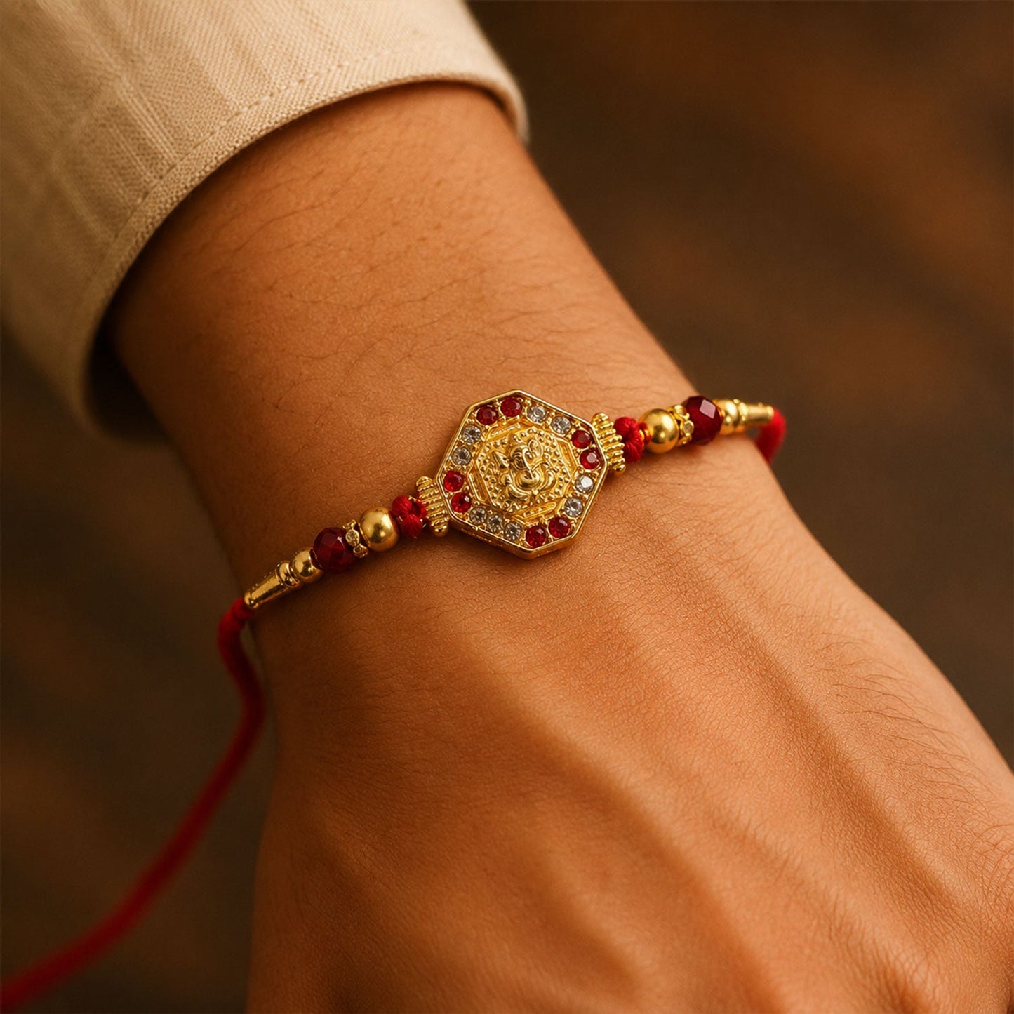 Close-up of Lord Ganesha Rakhi featuring vibrant red enamel and gold accents