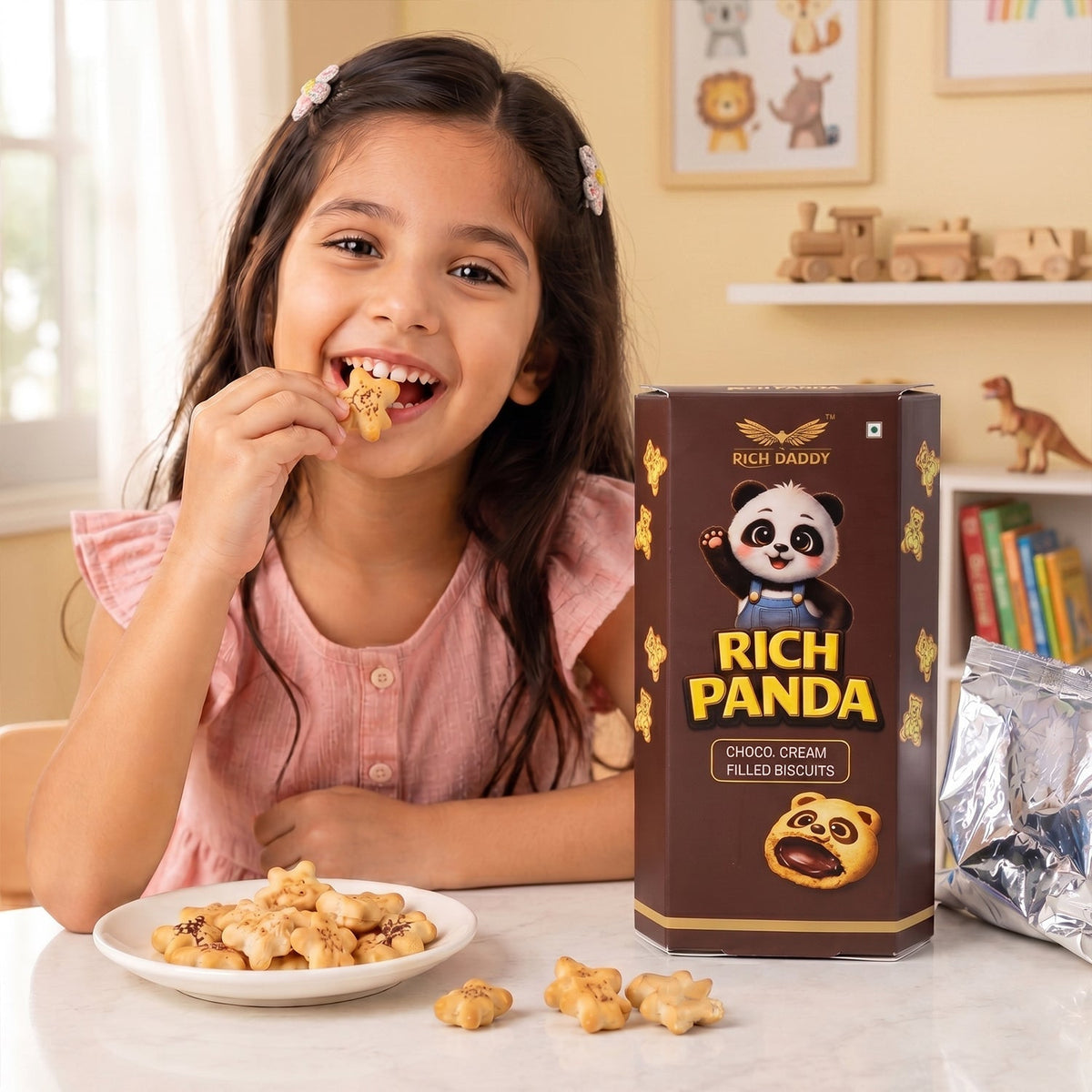 A smiling girl holds a panda biscuit to her mouth, next to a brown box and a plate of biscuits.