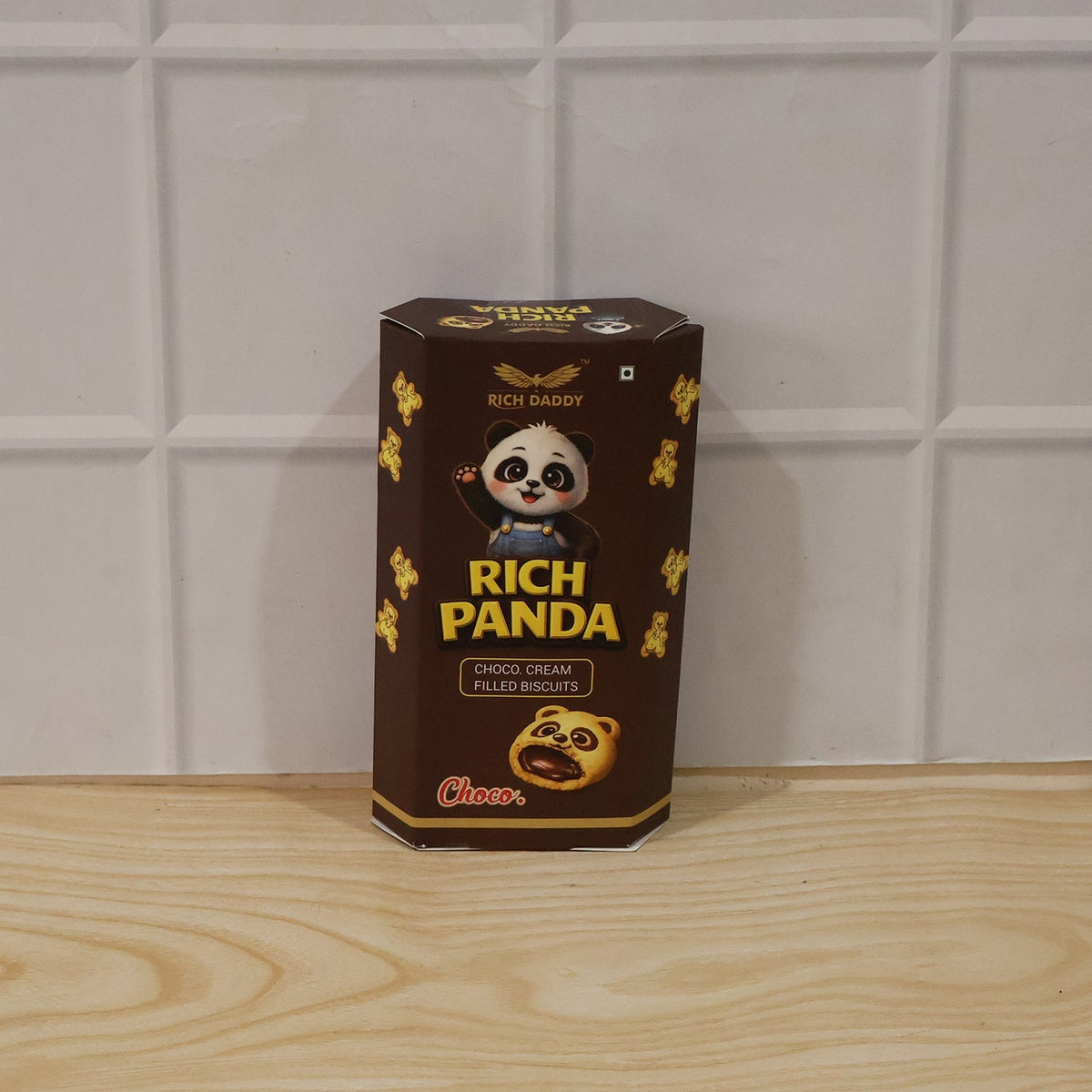 A brown hexagonal box of Rich Daddy Panda Choco Cream Filled Biscuits is placed on a light wooden surface.
