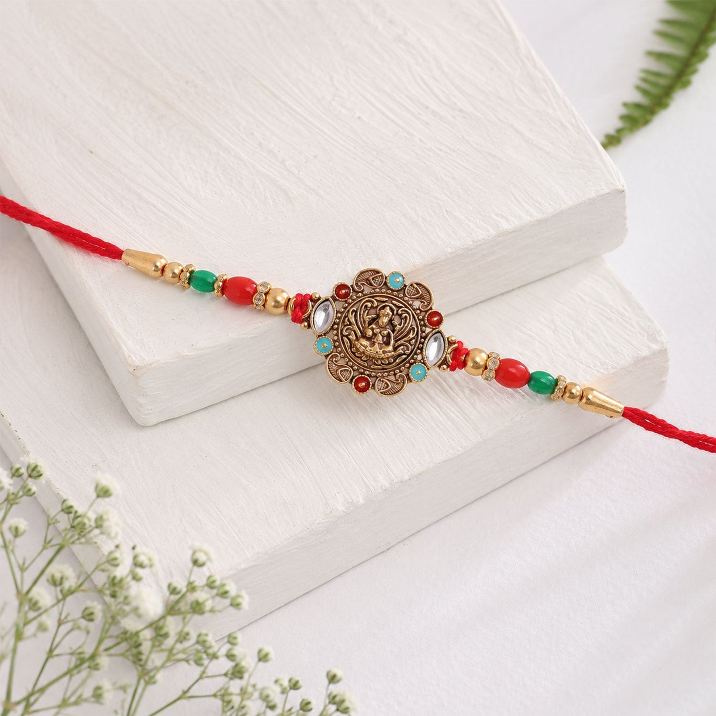 Stylish and festive rakhi featuring antique golden finish and vibrant beads.