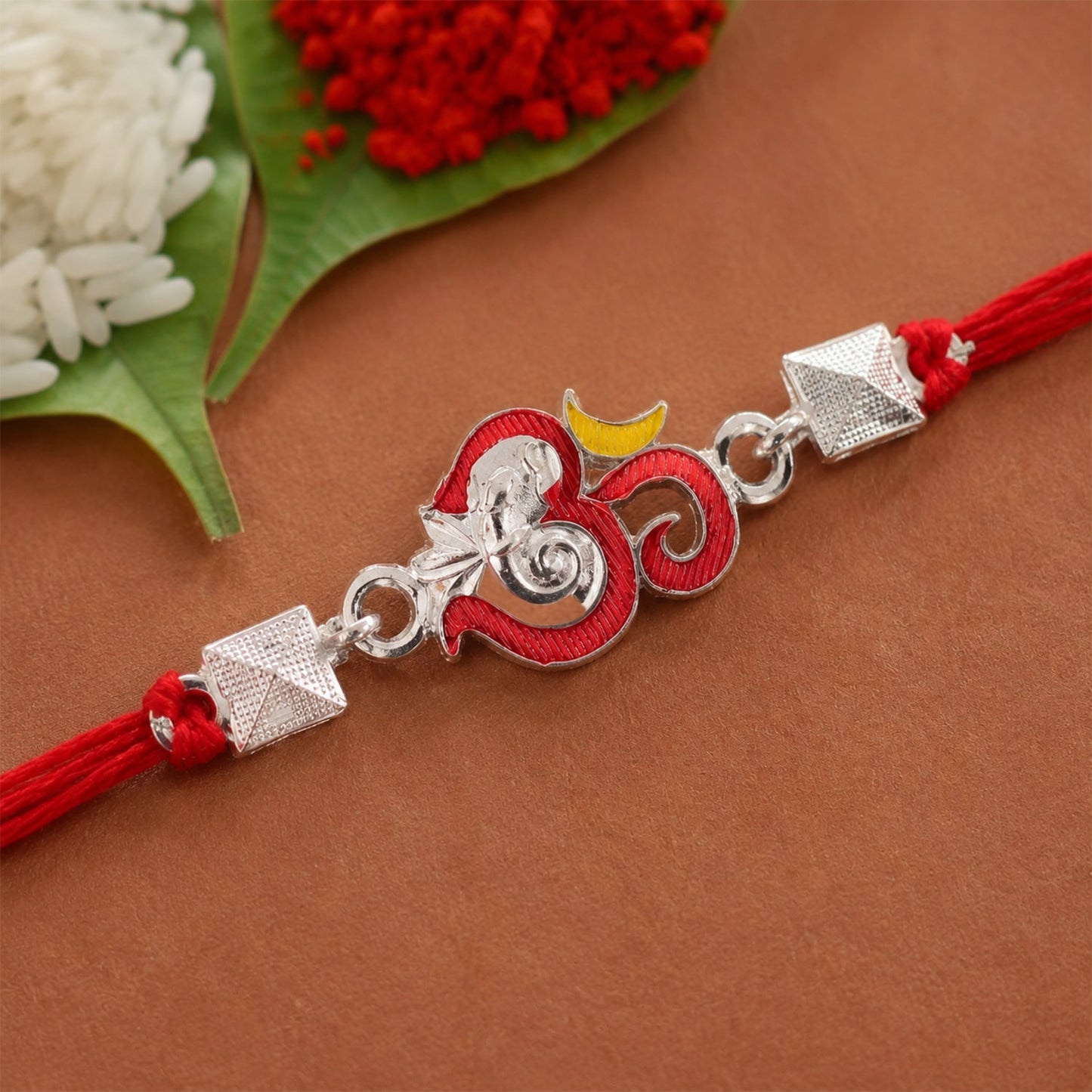 Close-up of silver Om Ganesha motif on festive rakhi with vibrant enamel details
