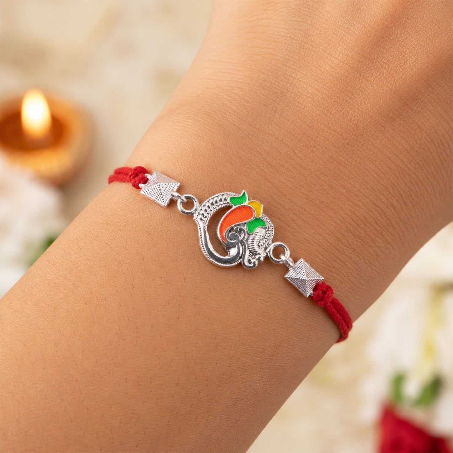 Close-up of Silver Om Ganesha Rakhi with vibrant enamel detailing
