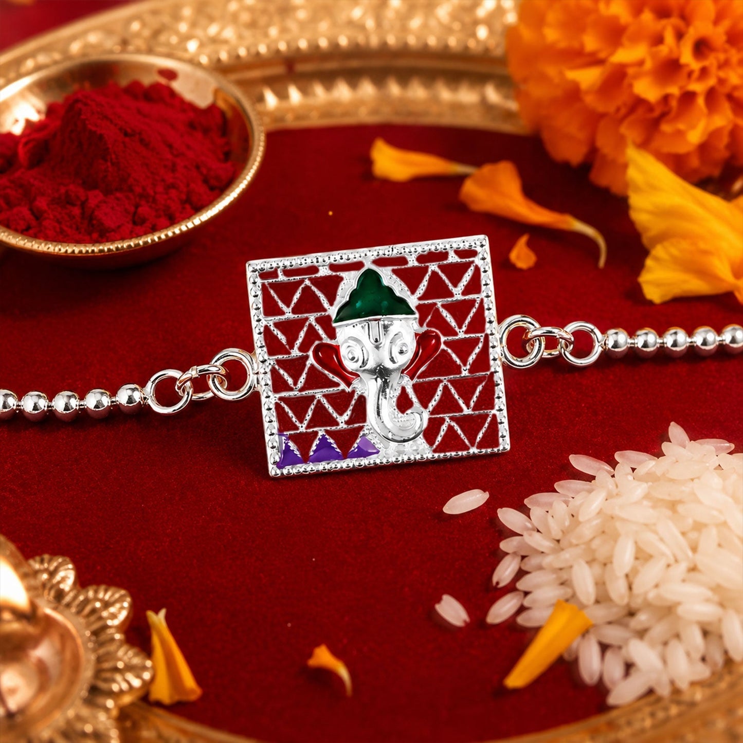 Silver Ganesha enamel rakhi with decorative thread and festive design