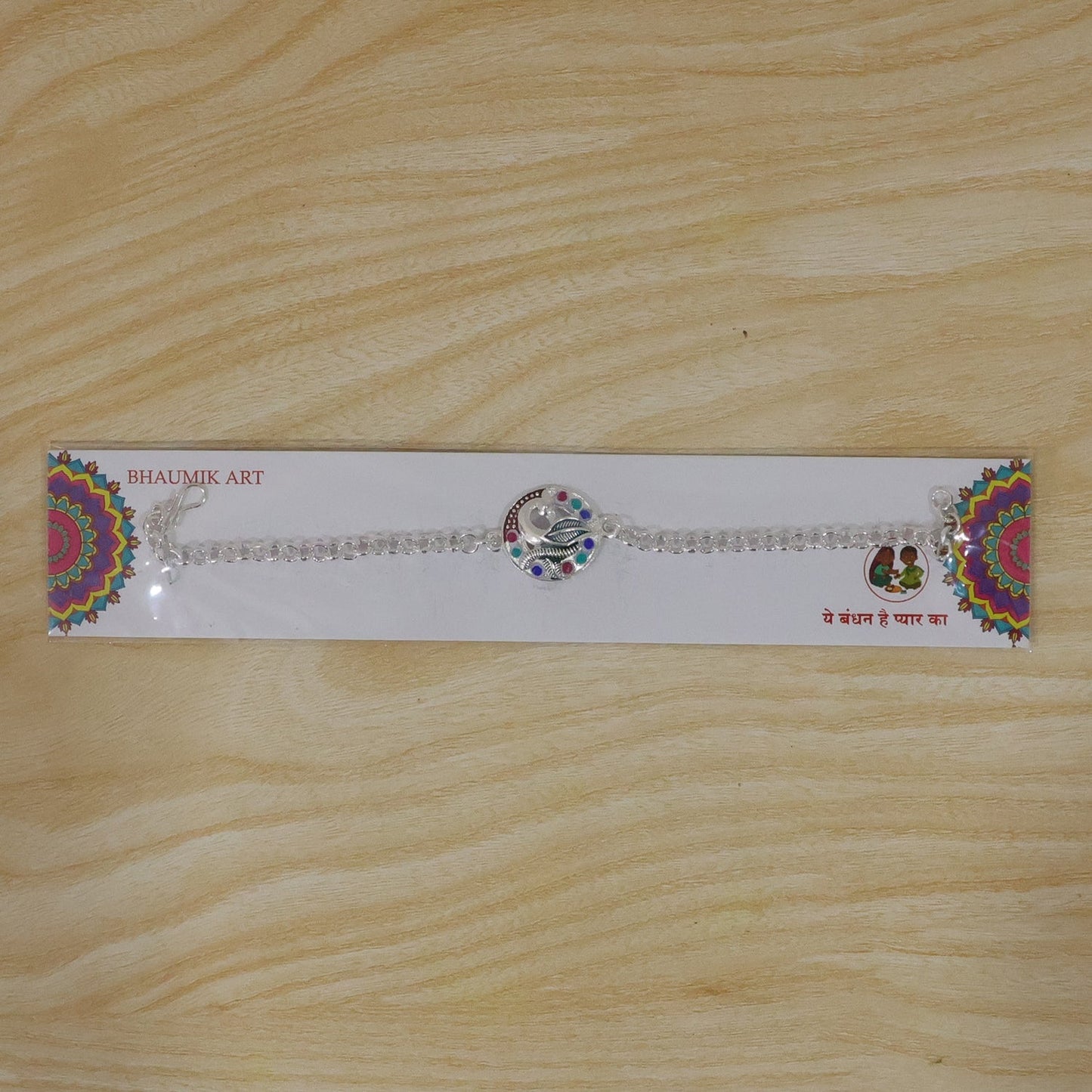 Front view of the colorful peacock motif enamel and stone traditional rakhi