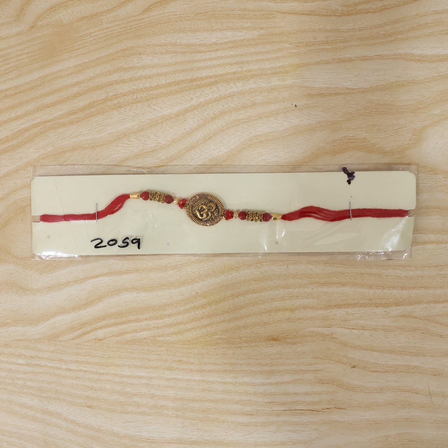 Antique Om coin Rakhi displayed on white background