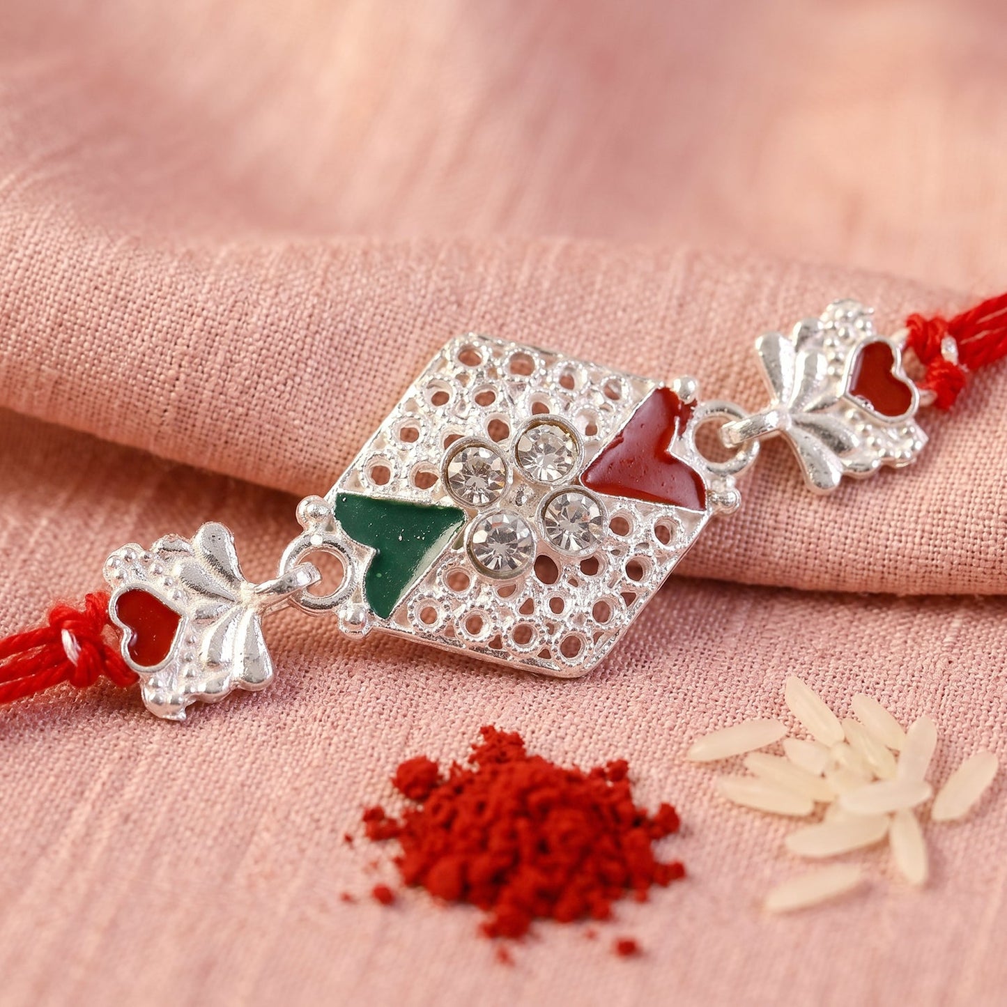 Festive rakhi showing red green stones and thread detail