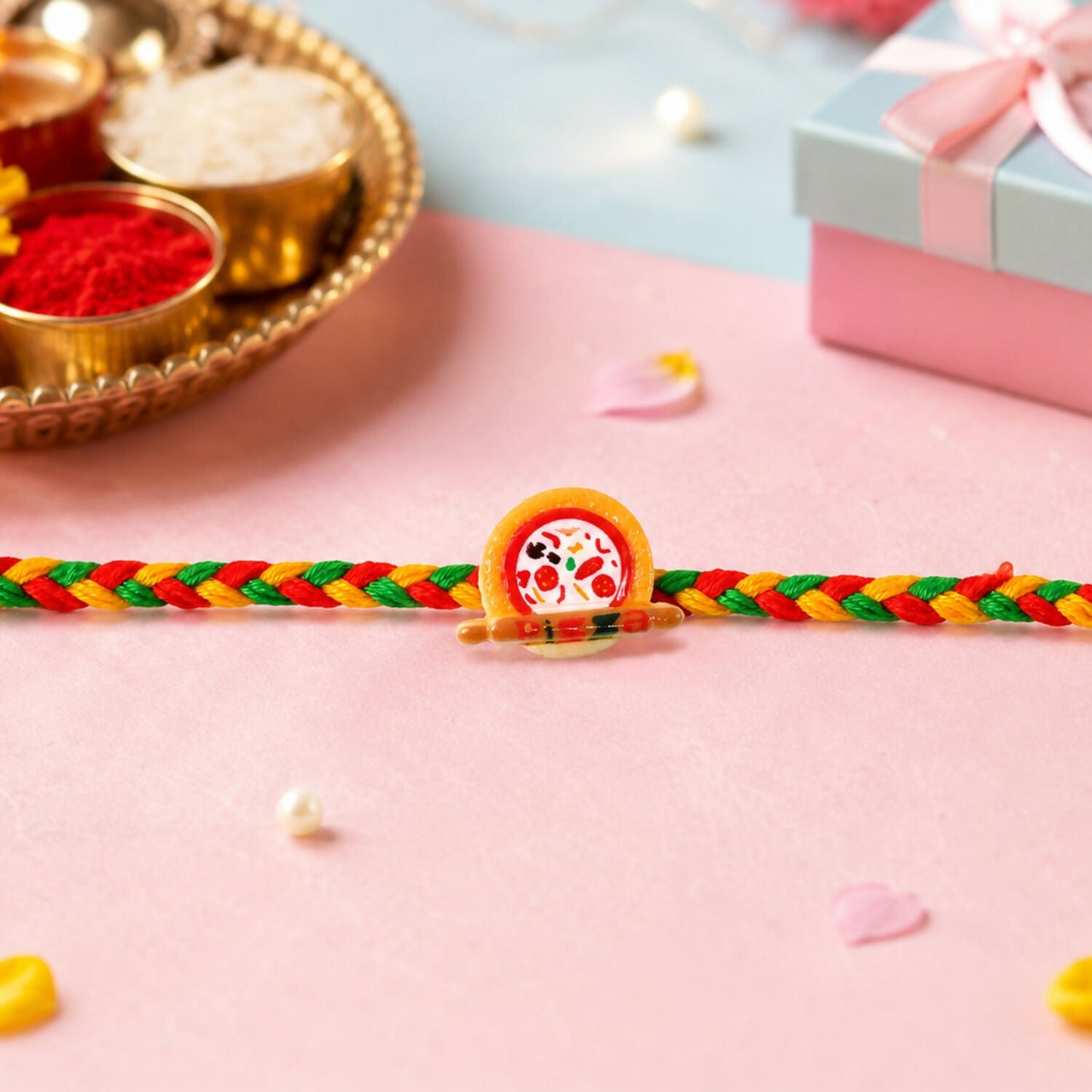 Close-up of kids rakhi with pizza charm and multicolor thread