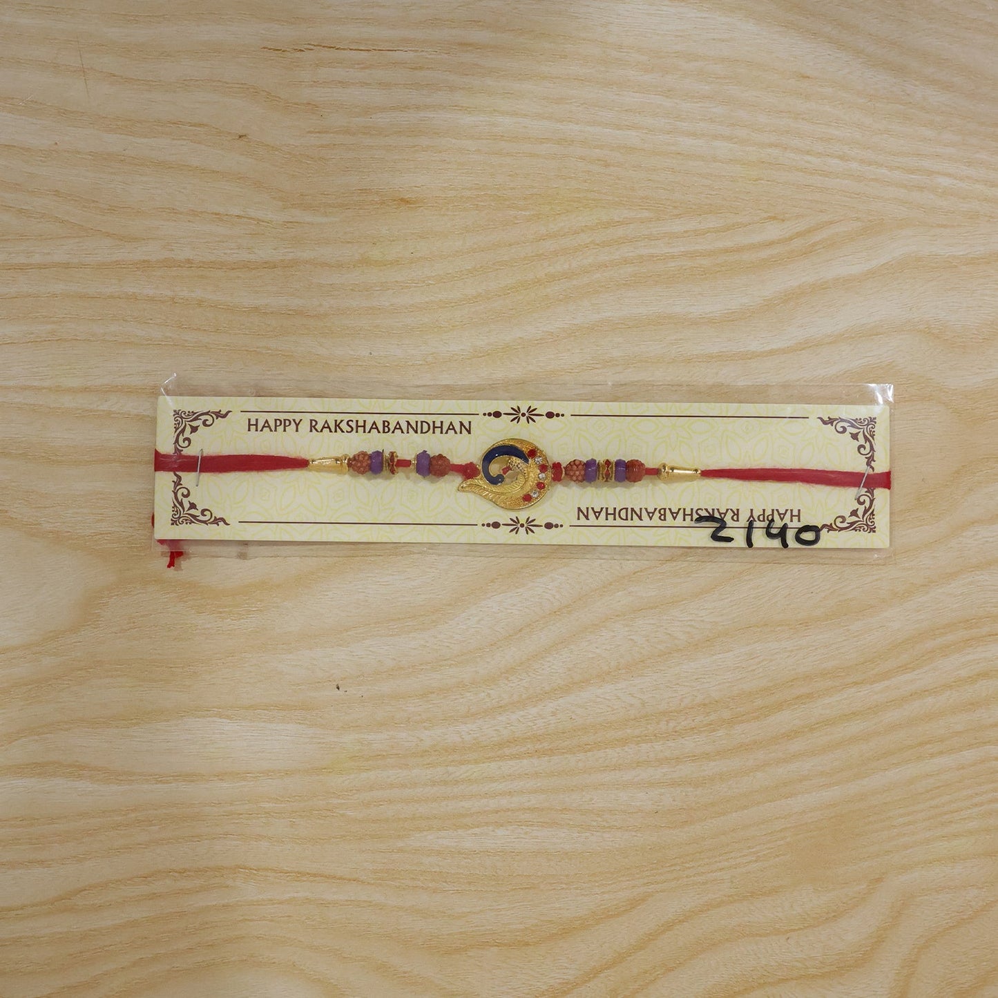 Side view of Rakhi with gold crescent frame and blue thread.