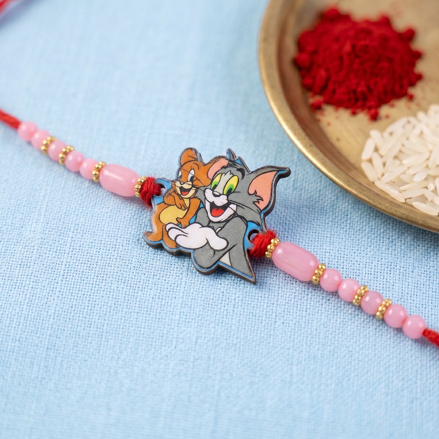 Festive kids rakhi featuring decorative pink beads and gold details